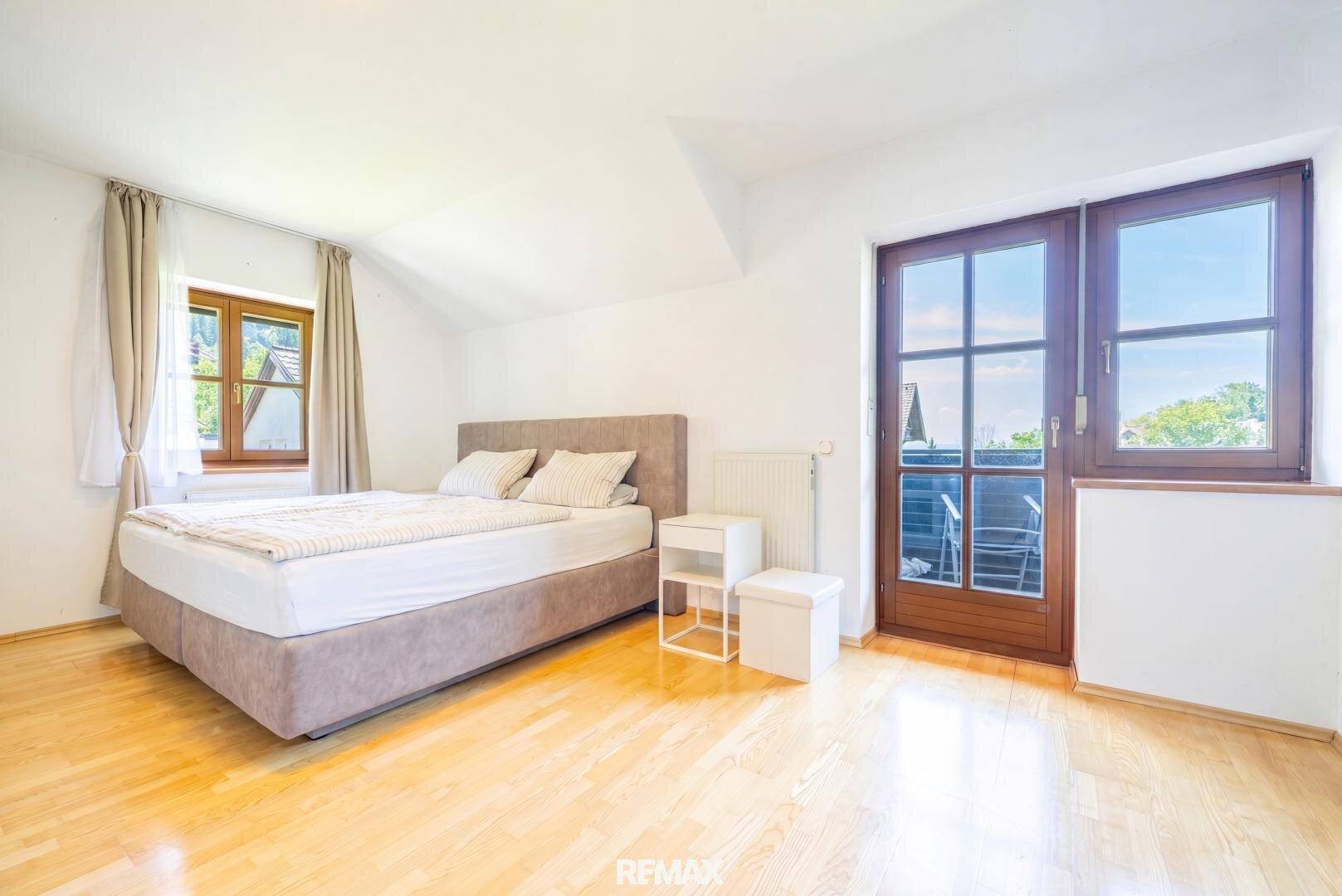Geräumiges Schlafzimmer mit Holzboden und Zugang zu einem französischen Balkon.