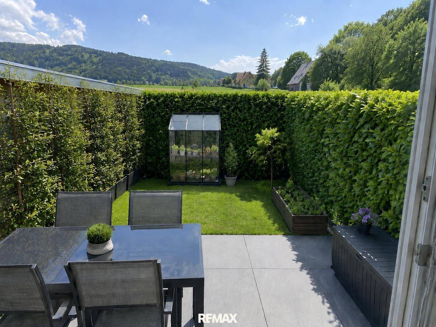 Gepflegter Garten mit Terrasse, Hecken, Rasenfläche und einem kleinen Gewächshaus.