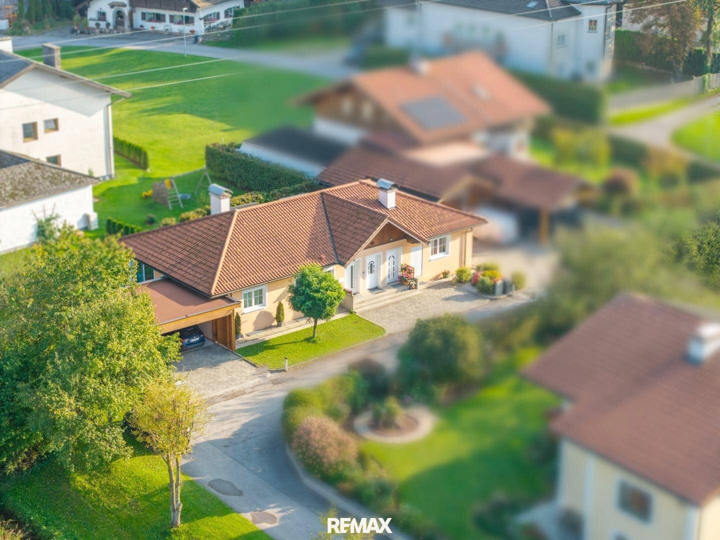 Luftaufnahme eines Einfamilienhauses mit Satteldach, umgeben von Grünflächen und anderen Wohnhäusern.