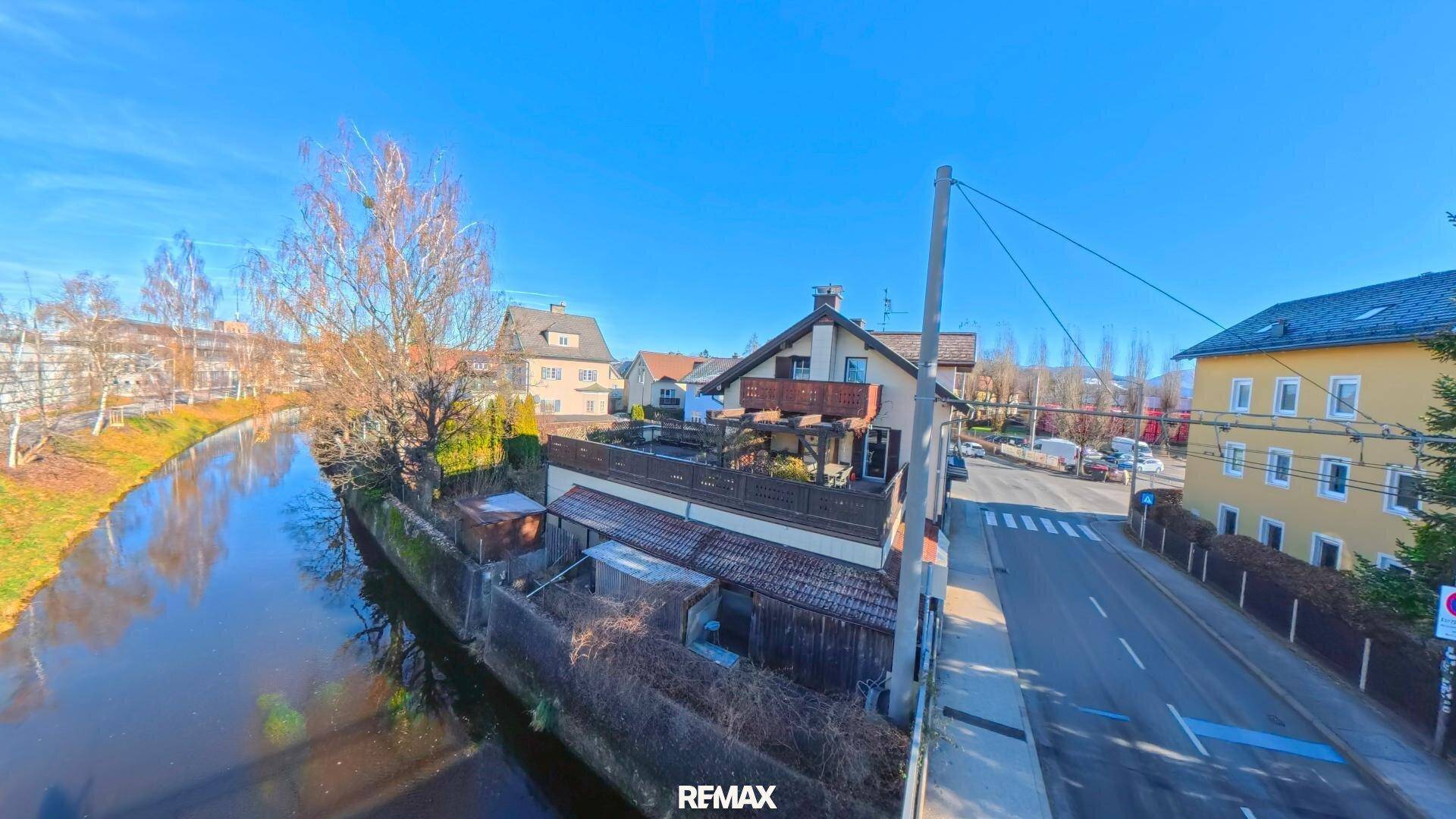 Überblick über das Anwesen mit angrenzendem Kanal und umliegenden Wohnhäusern unter blauem Himmel.
