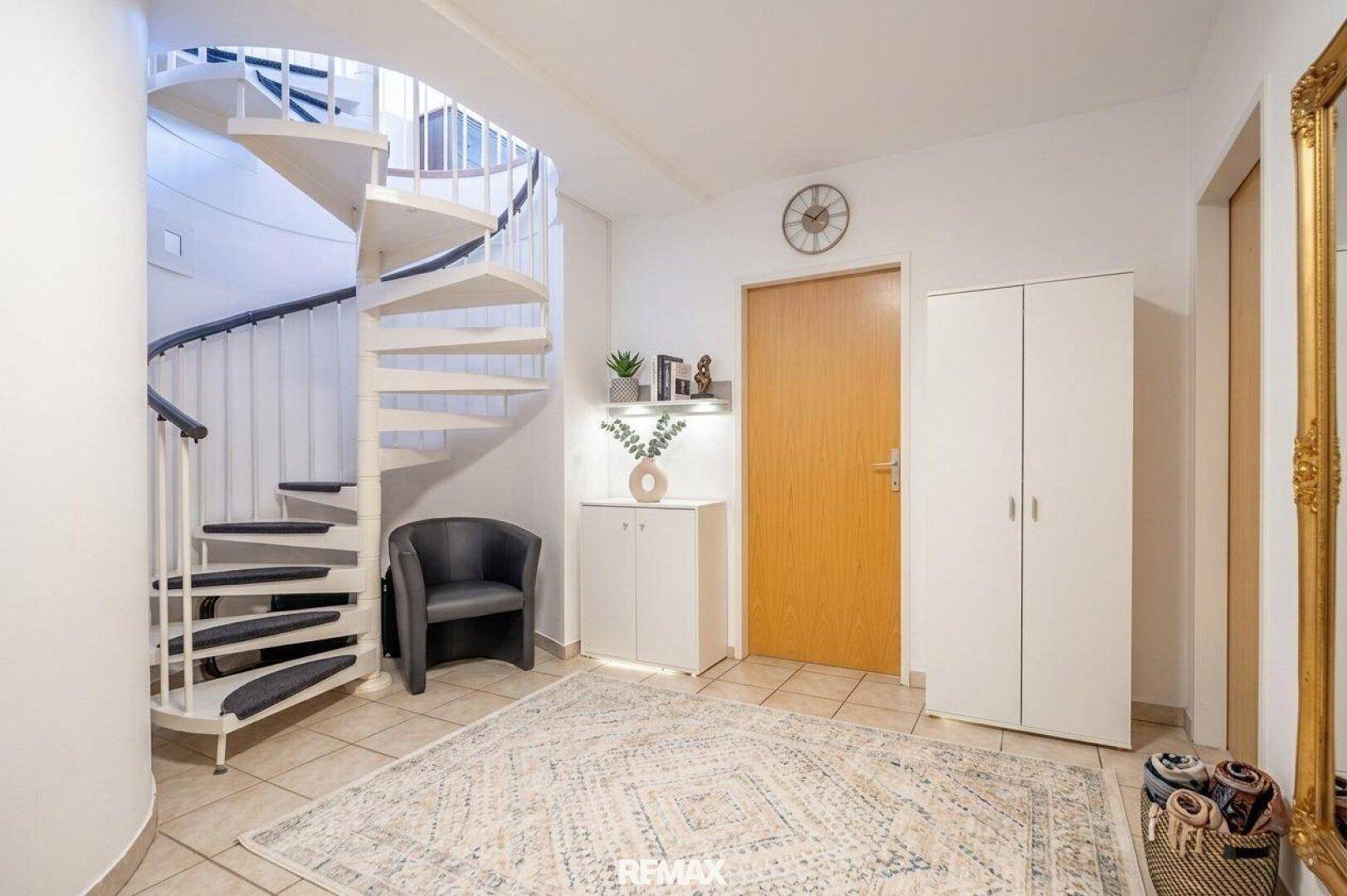 Heller Eingangsbereich mit Wendeltreppe, Fliesenboden und Garderobenschränken.