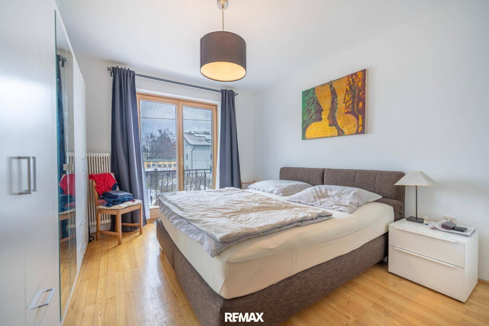 Schlafzimmer mit Doppelbett, Parkettboden und Balkonzugang, hell und freundlich gestaltet.