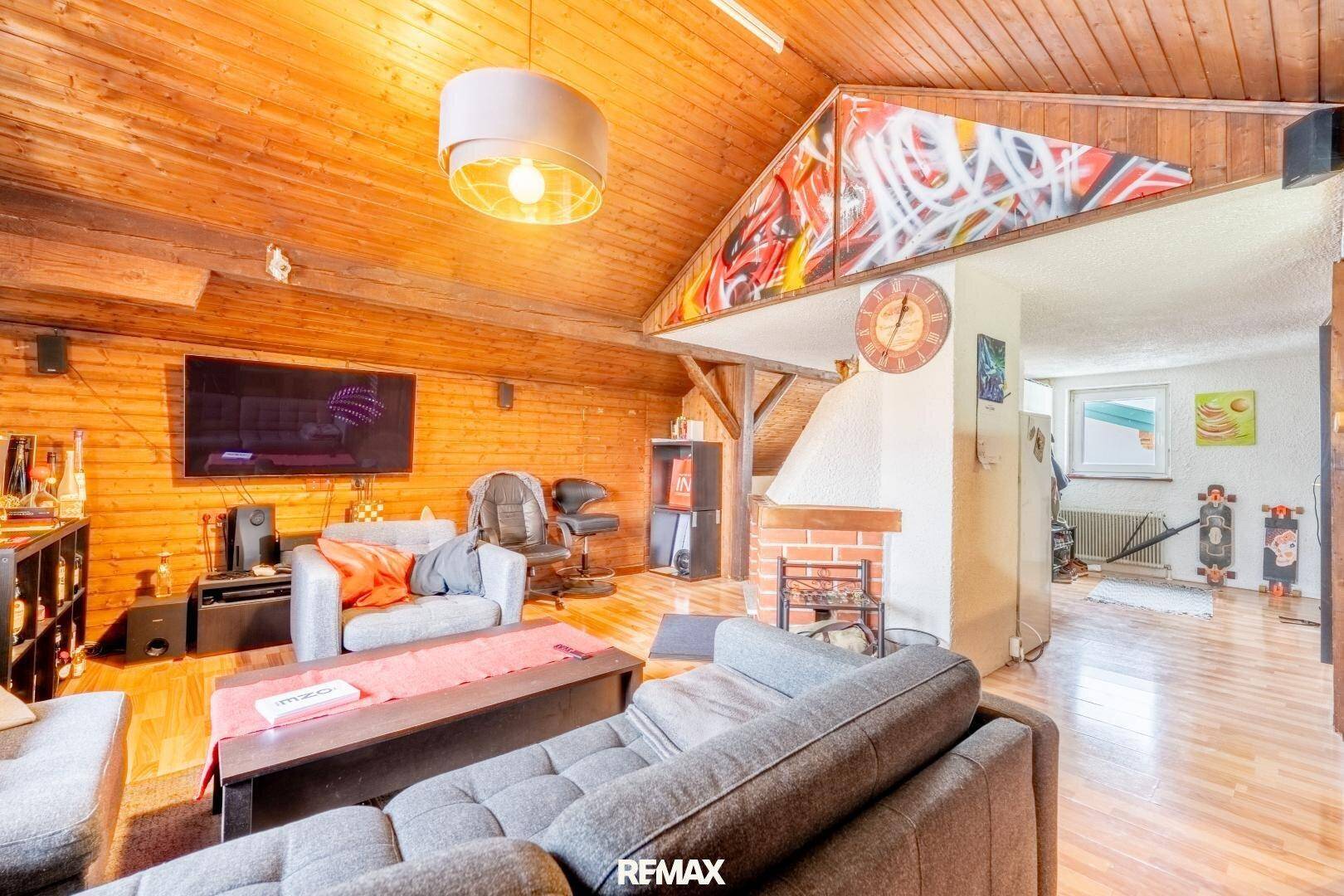 Gemütliches Wohnzimmer im Dachgeschoss mit Holzverkleidung, Kamin und rustikalem Charme.