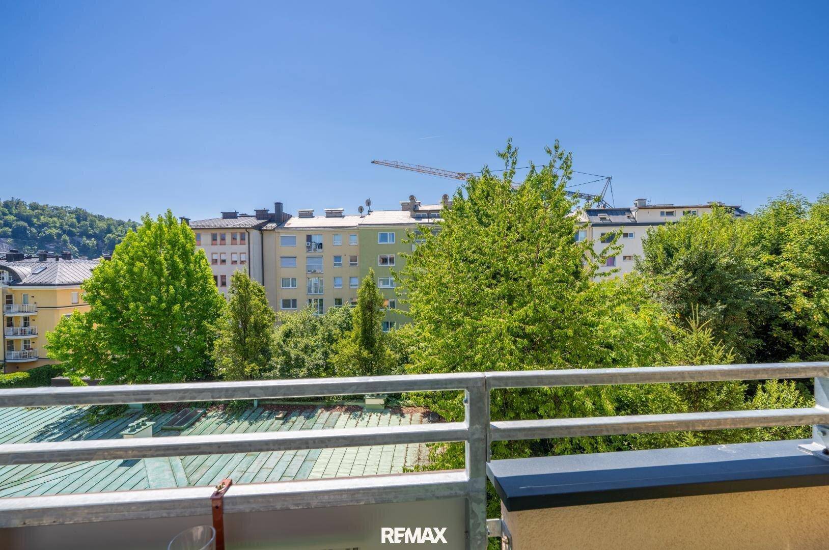 Balkon mit weitem Blick über grüne Bäume und die umliegenden Gebäude der Stadt.