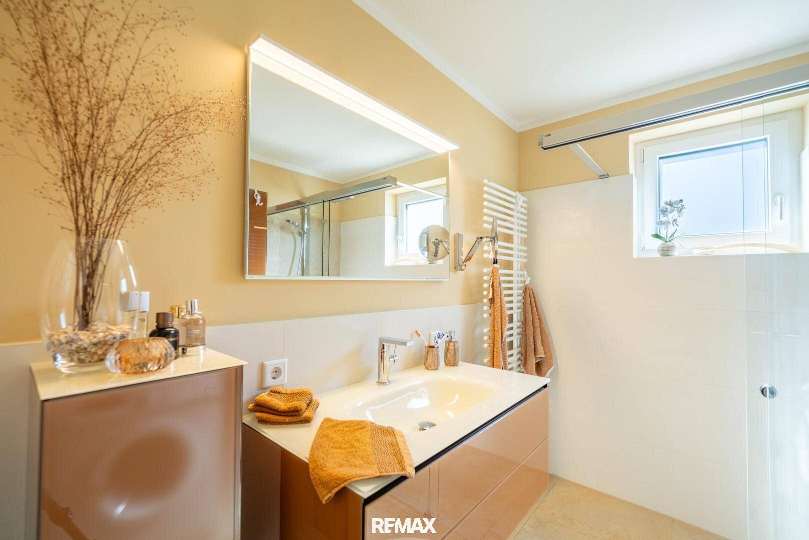 Modernes Badezimmer mit Einzelwaschbecken, großem Spiegel und beheiztem Handtuchhalter, mit Fenster.