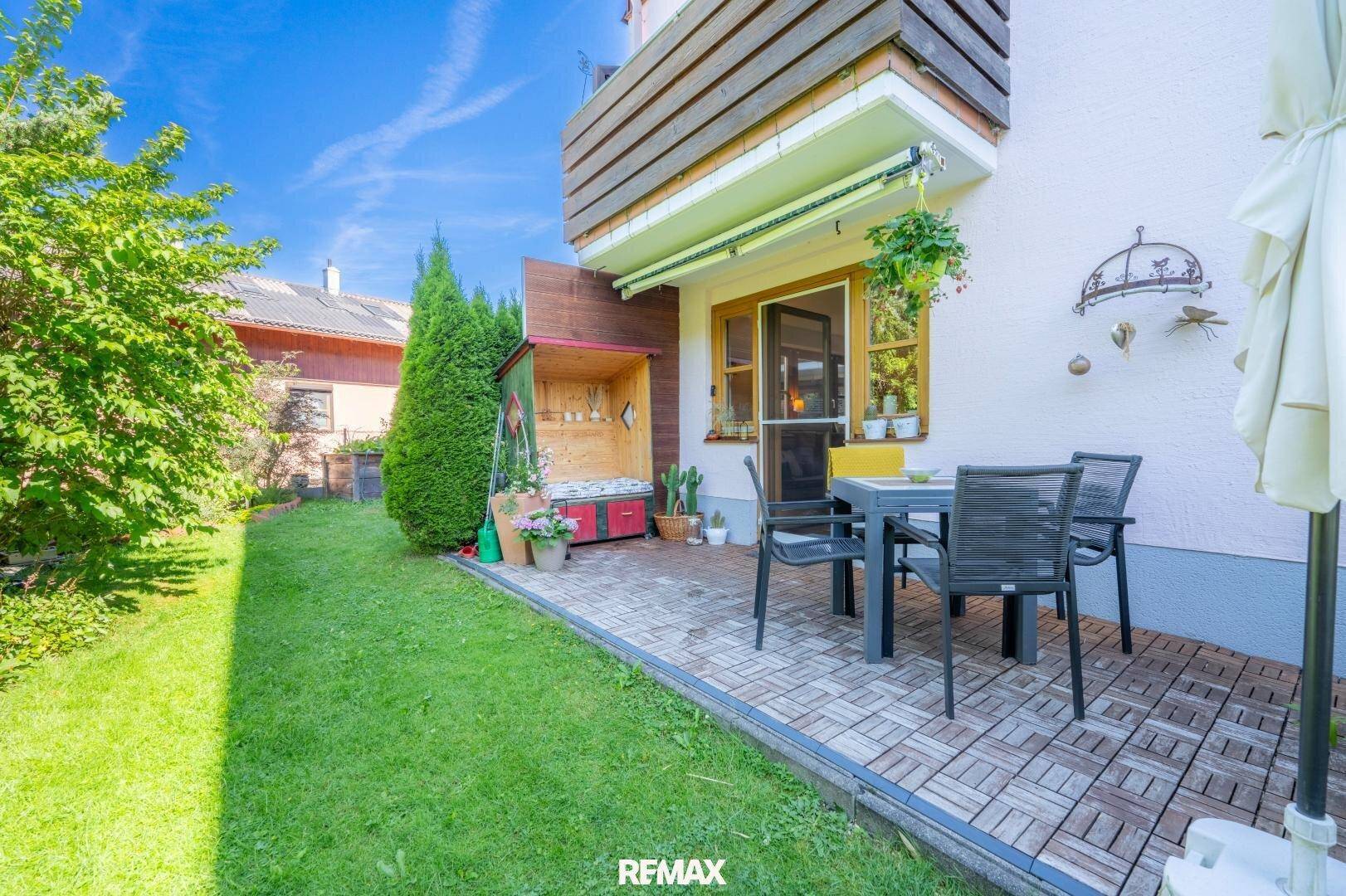 Sonniger Terrassenbereich mit Gartenmöbeln und direktem Zugang zum grünen Garten, ideal zum Entspannen.