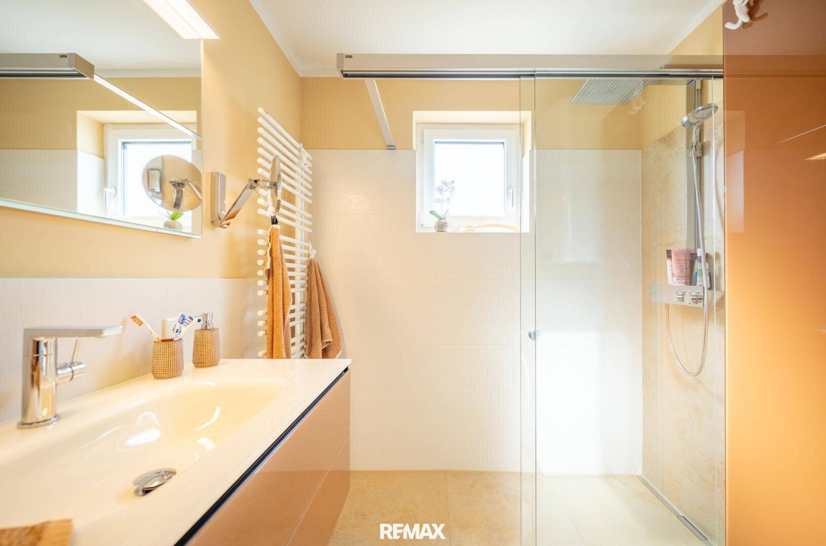 Helles Badezimmer mit ebenerdiger Dusche, Regendusche und Einzelwaschbecken, mit Fenster.