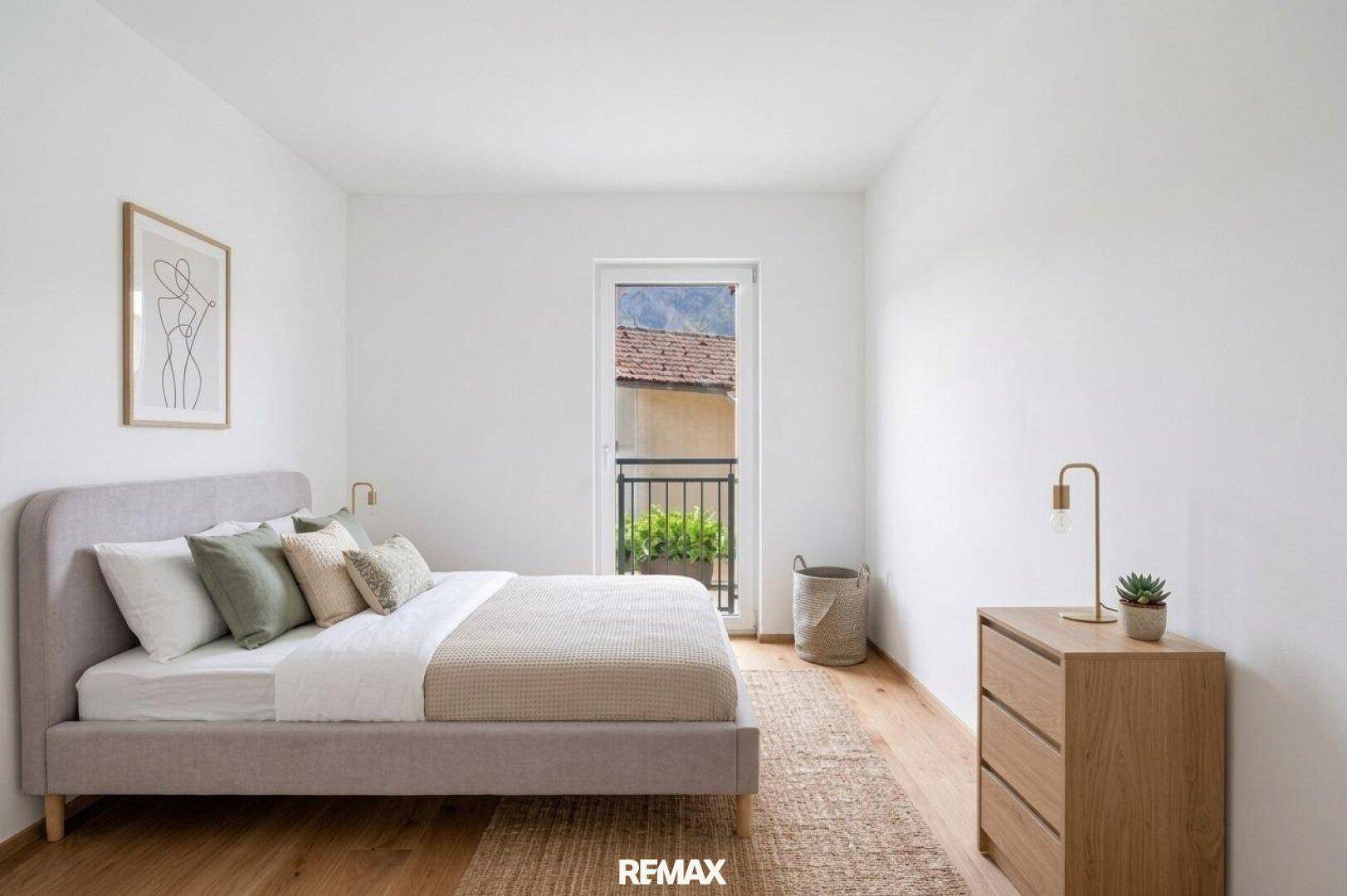 Schlafzimmer mit Doppelbett, Holzboden und Zugang zu einem französischen Balkon.