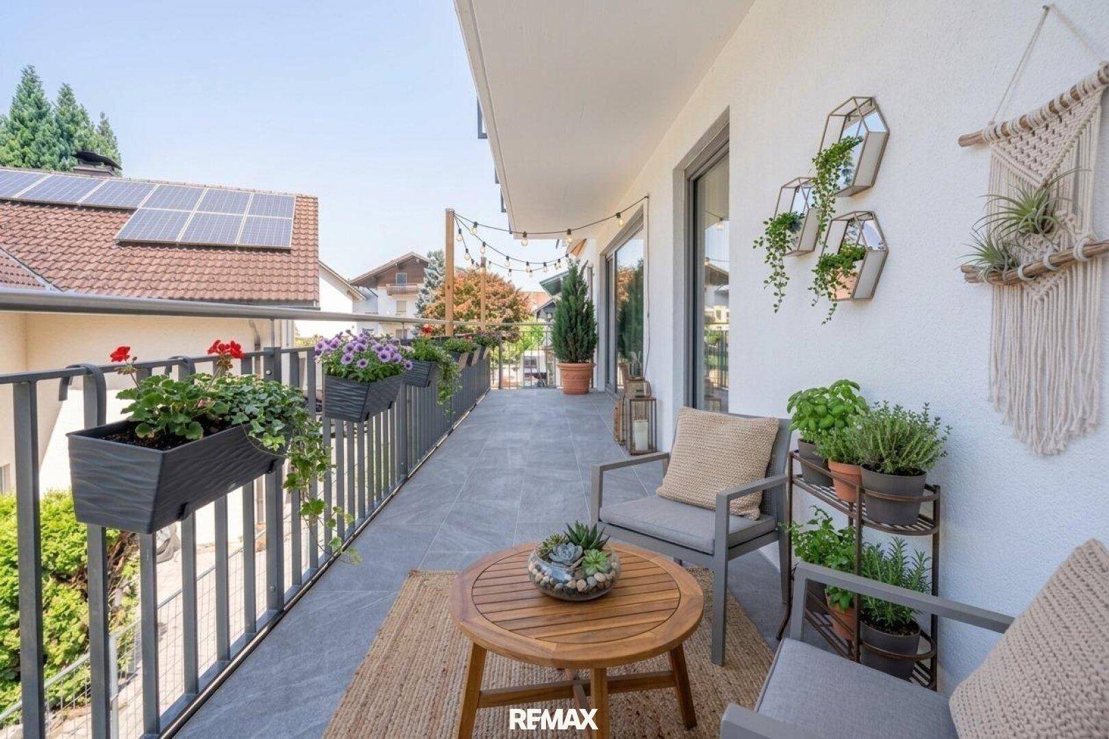 Langer Balkon mit Sitzgelegenheiten, Pflanzen und Blick auf die Umgebung.