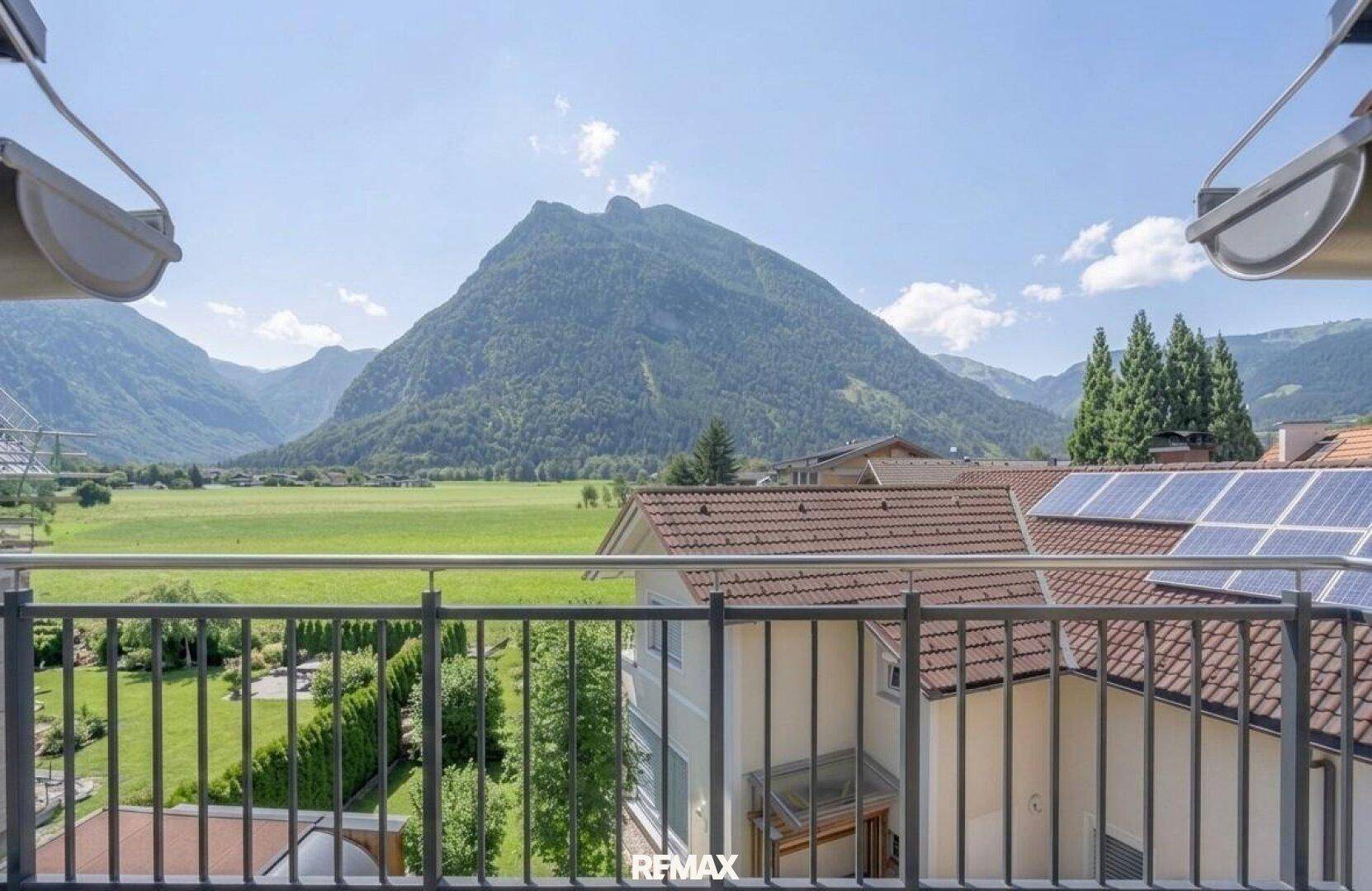 Balkon mit weitem Blick auf die umliegende Berglandschaft und grüne Felder.