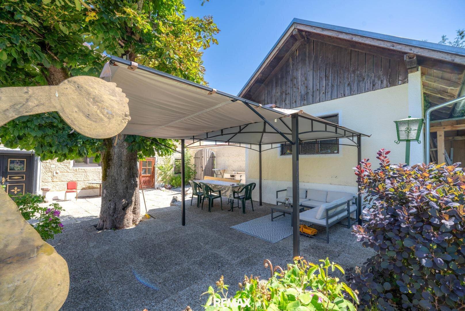 Überdachte Terrasse mit Esstisch und Sitzgelegenheiten, ideal für Mahlzeiten im Freien.