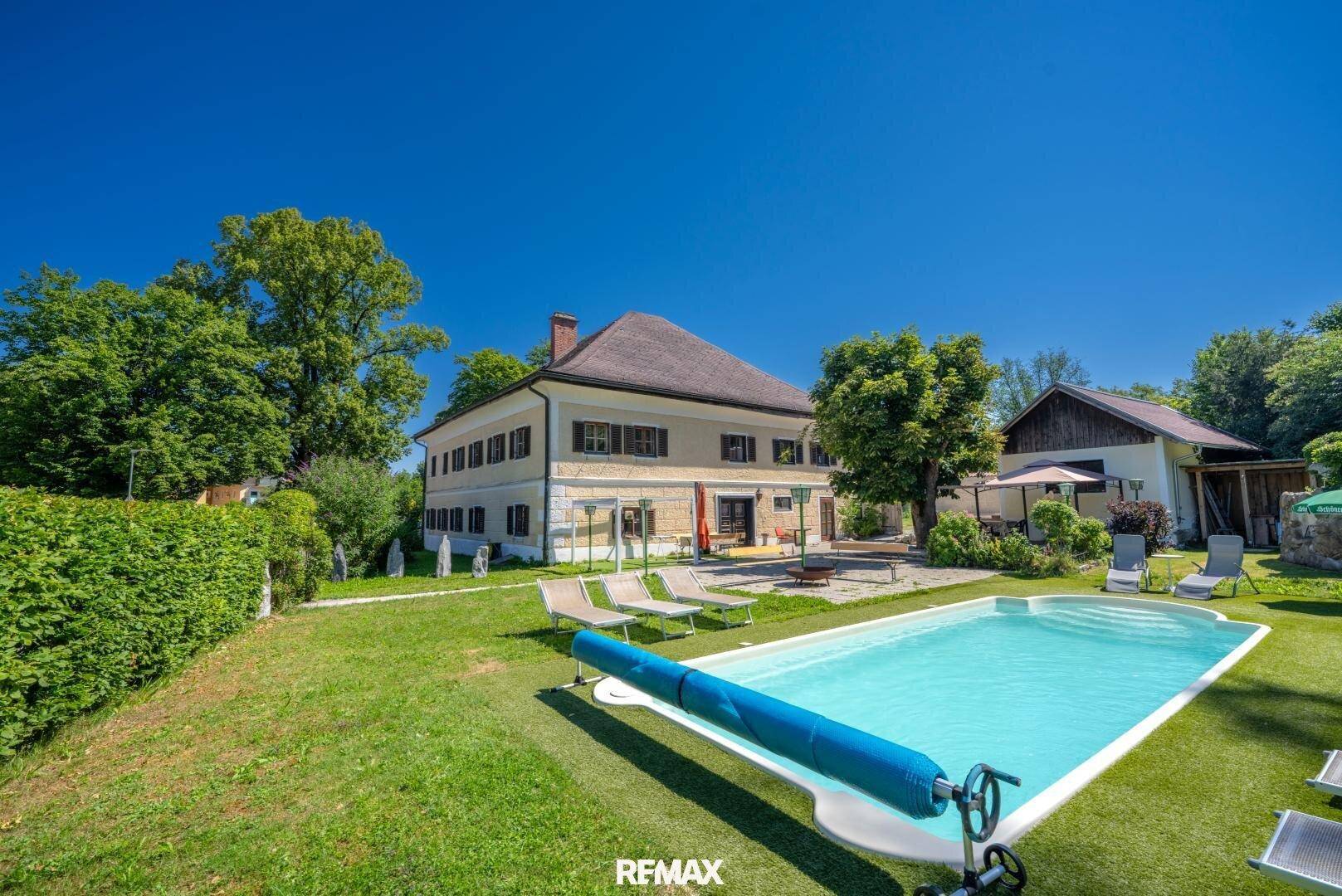 Gepflegter Garten mit Pool und Liegestühlen, umgeben von üppigem Grün und Bäumen.