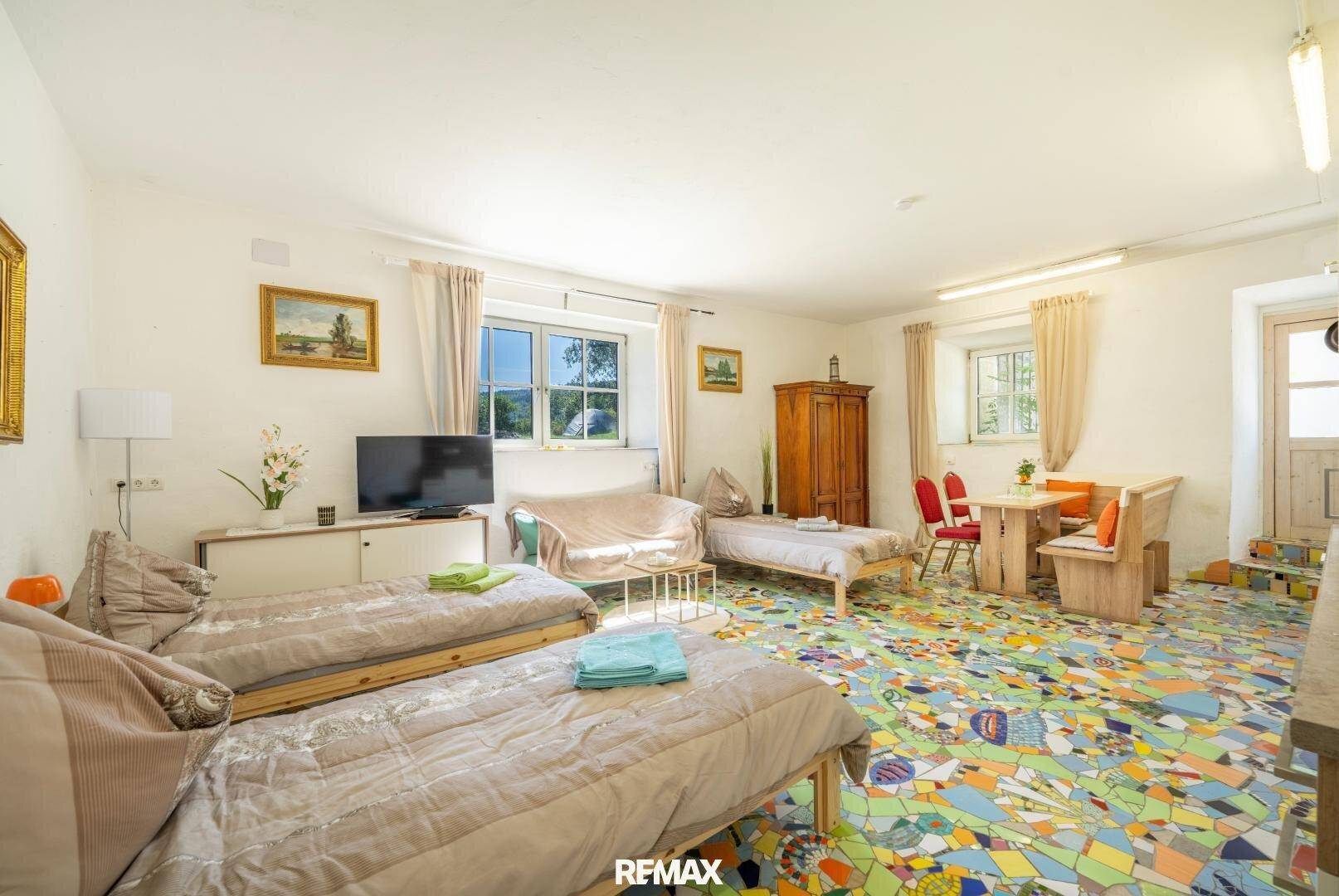 Gemütliches Schlafzimmer mit Mosaikboden, mehreren Betten und einem kleinen Essbereich.