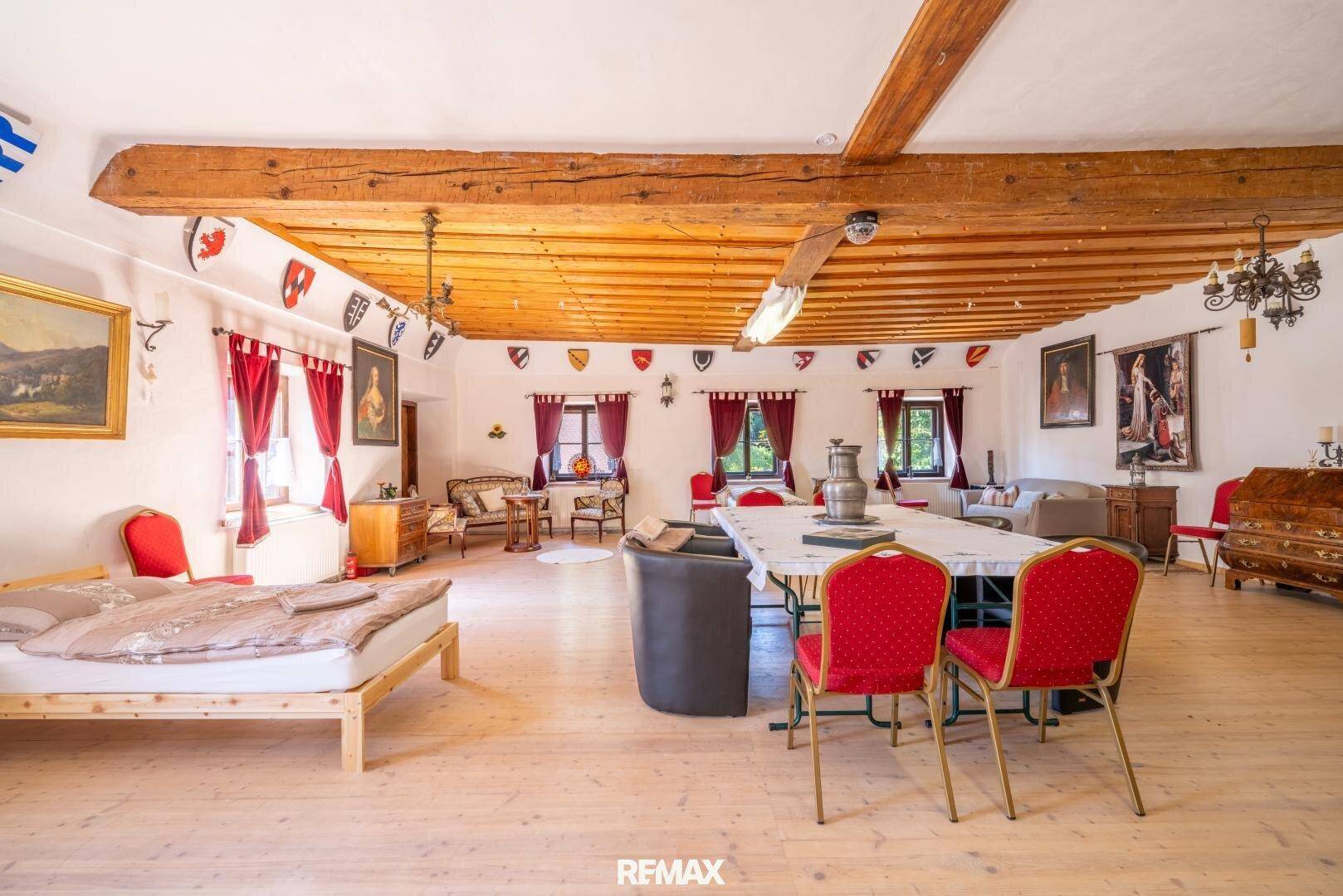 Großer Wohnraum mit Holzbalkendecke, Holzdielenboden und traditioneller Dekoration.