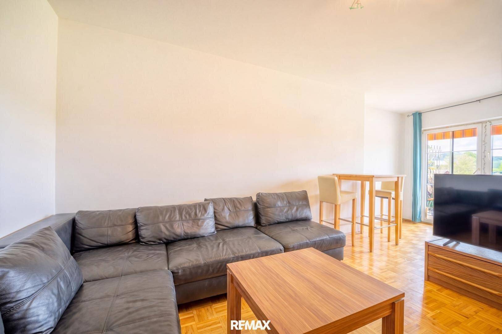 Wohnzimmer mit großer Eckcouch, Couchtisch und Essbereich am Fenster.