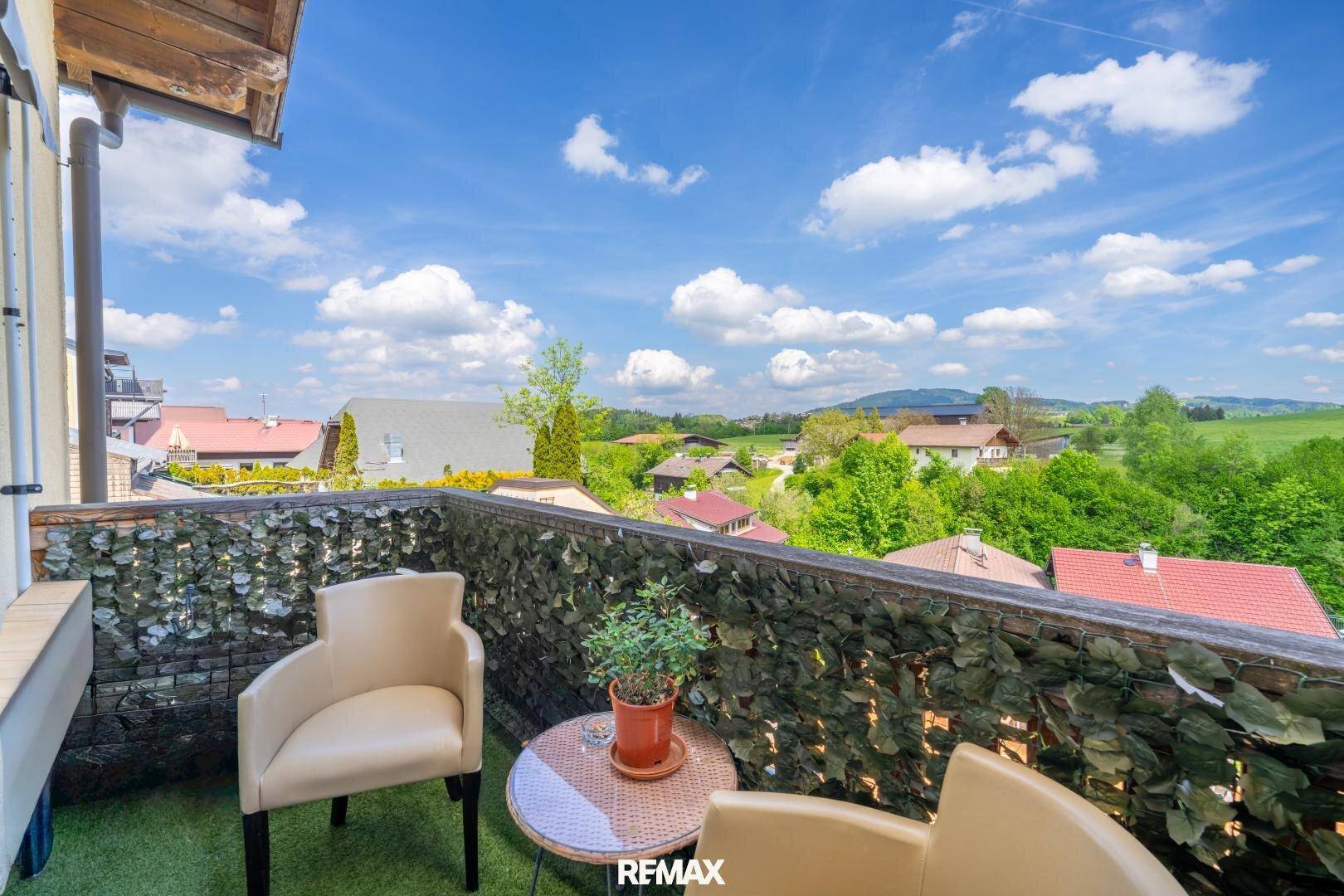 Gemütlicher Balkon mit Sitzgelegenheiten und weitem Blick über die grüne Landschaft.