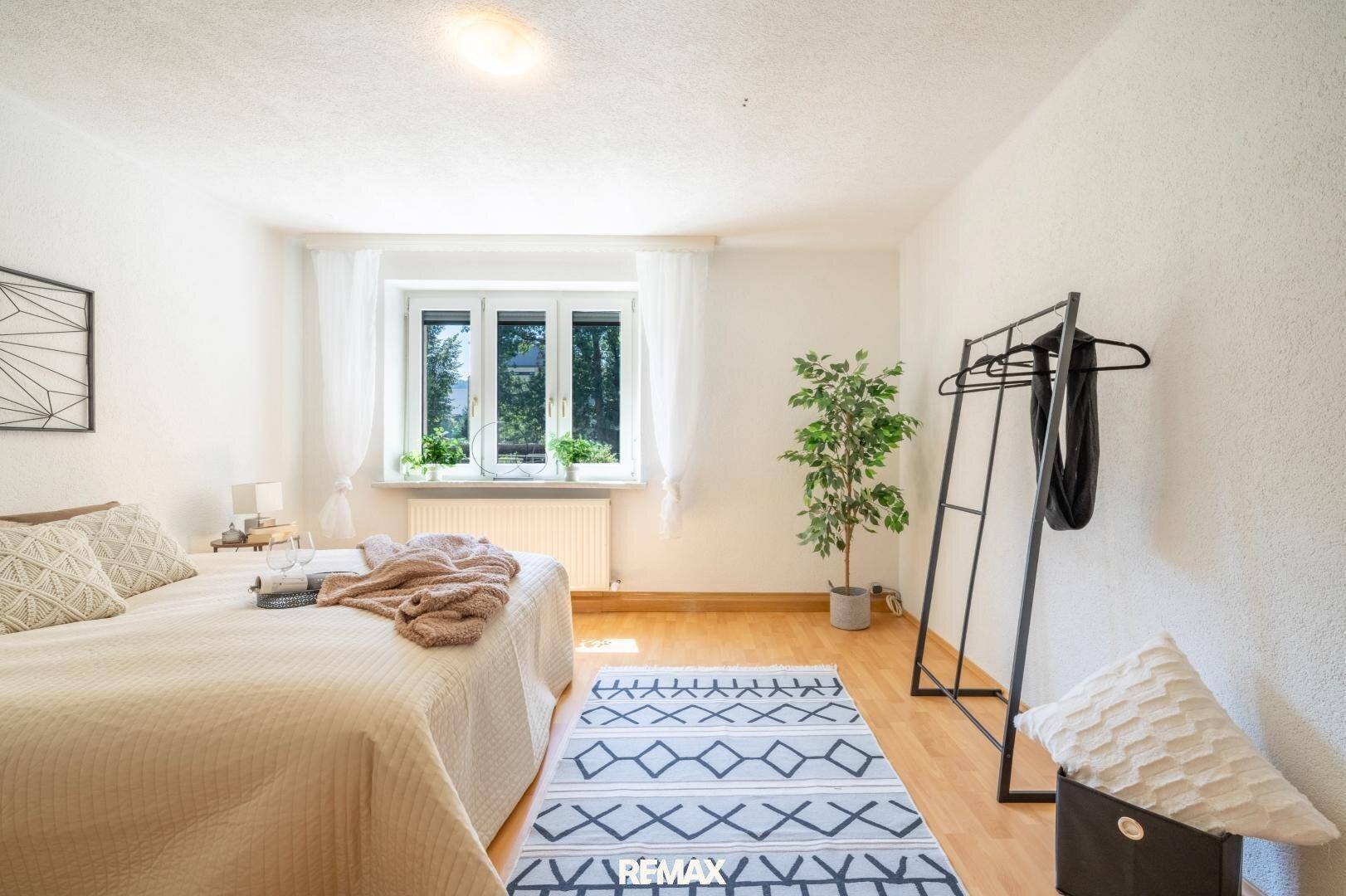Geräumiges Schlafzimmer mit Holzboden, großem Fenster und Kleiderständer.