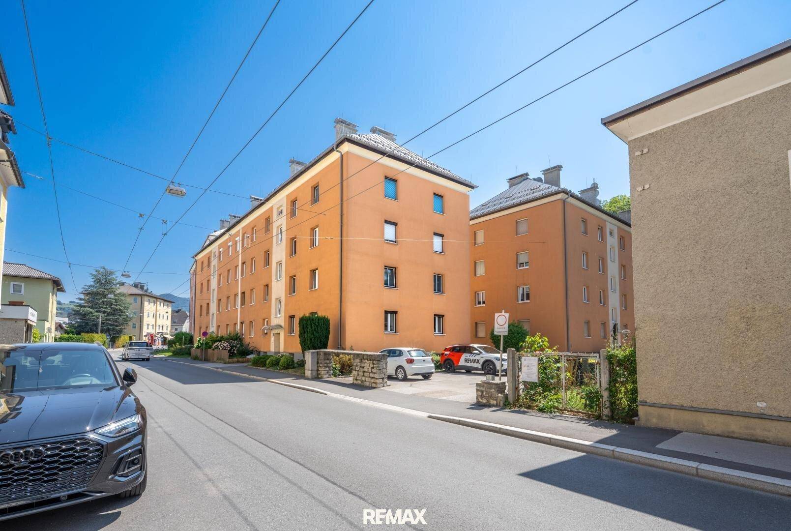 Wohngebäude in städtischer Umgebung mit gepflegter Fassade und Parkplätzen.