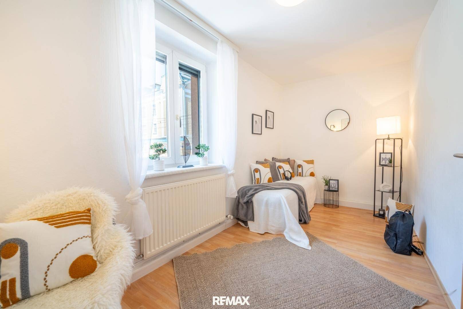 Gemütliches Schlafzimmer mit Parkettboden, großem Fenster und moderner Dekoration.