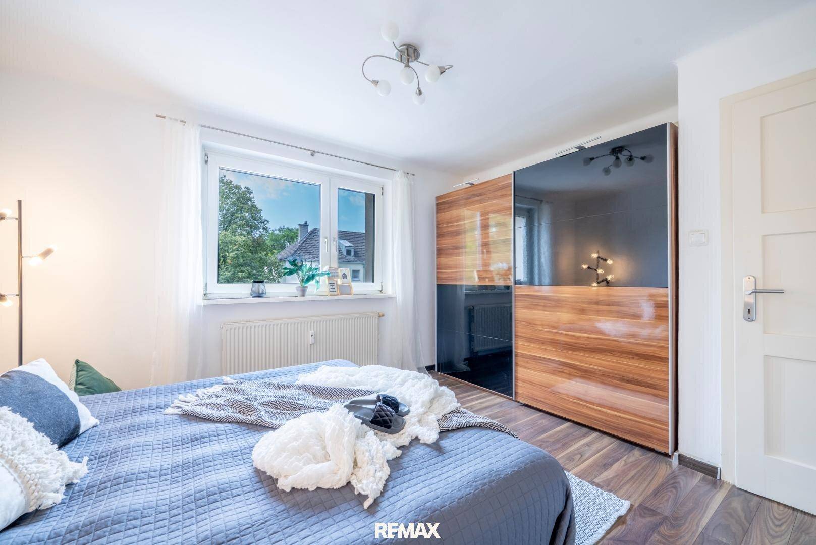 Schlafzimmer mit großem Einbauschrank und Fenster, das viel natürliches Licht hereinlässt.