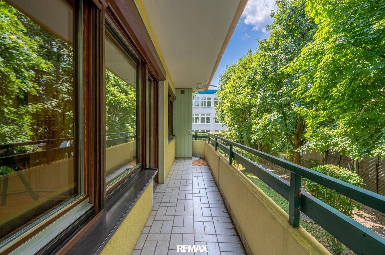 Langer Balkon mit Fliesenboden und Blick ins Grüne sowie auf die Umgebung.