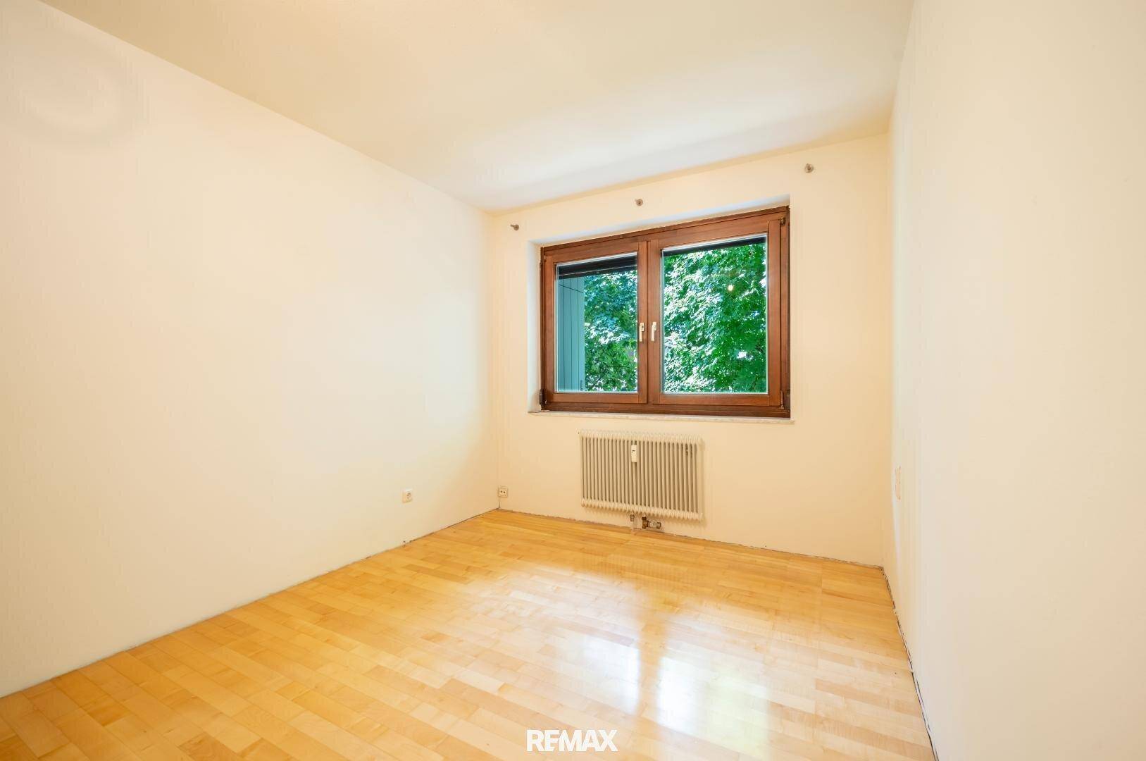 Helles Zimmer mit Parkettboden und Fenster mit Blick ins Grüne, ideal als Schlaf- oder Arbeitszimmer.