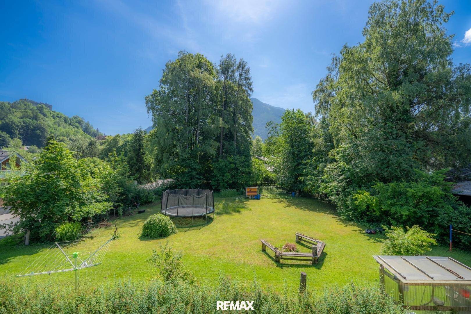 Großer, gepflegter Garten mit Rasenfläche, Trampolin und gemütlichen Sitzgelegenheiten im Freien.