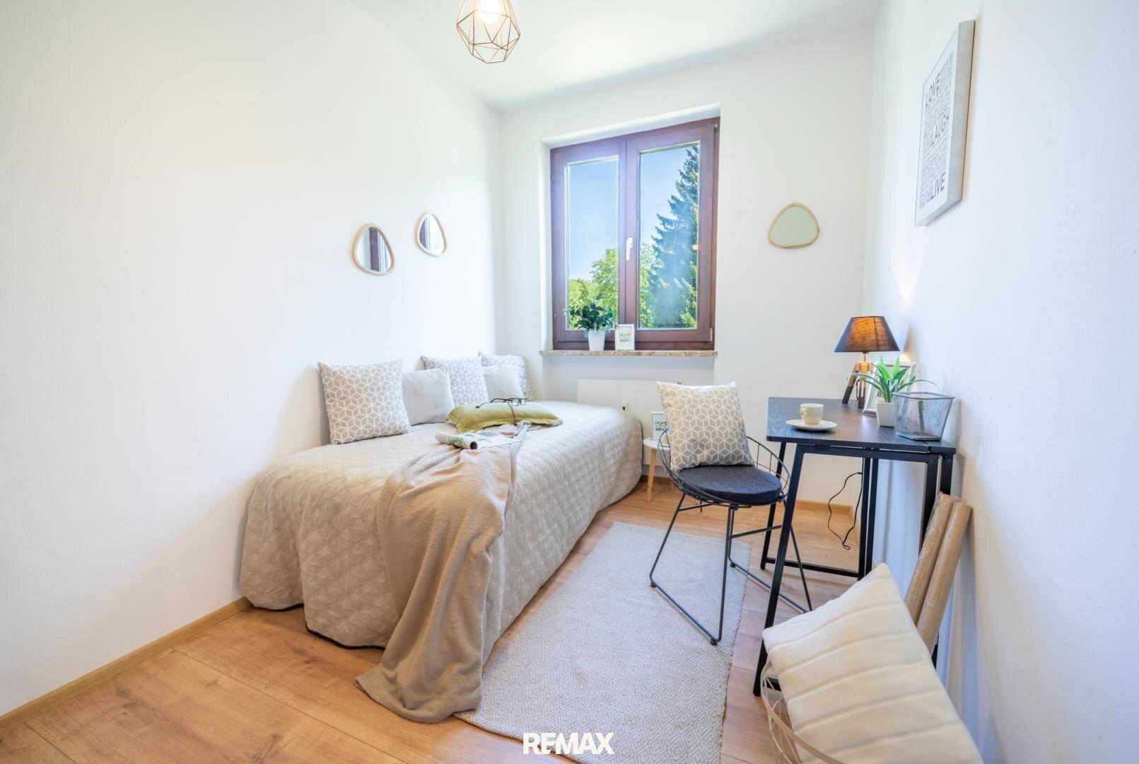 Kleines Schlafzimmer oder Arbeitszimmer mit Einzelbett, Schreibtisch und warmem Holzboden.