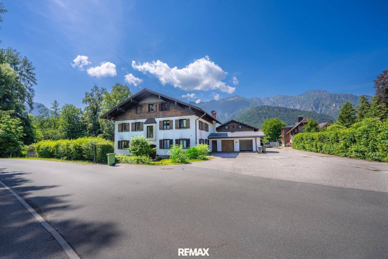 Traditionelles Haus mit Bergblick und großem Vorplatz in einer idyllischen ländlichen Umgebung.