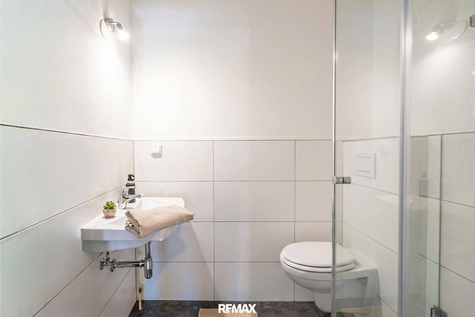 Modernes Badezimmer mit Dusche, WC und Waschbecken in schlichtem, funktionalem Design.