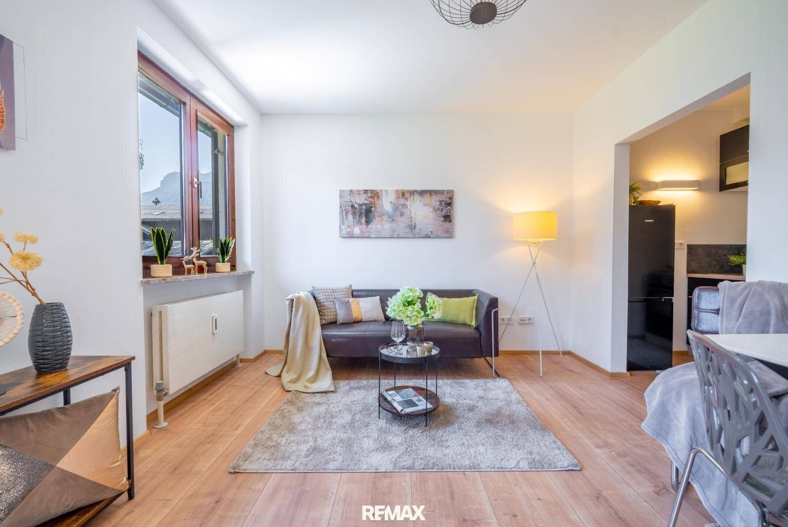 Gemütlicher Wohnbereich mit Sofa, Teppich und offener Verbindung zur praktischen Küchenzeile.
