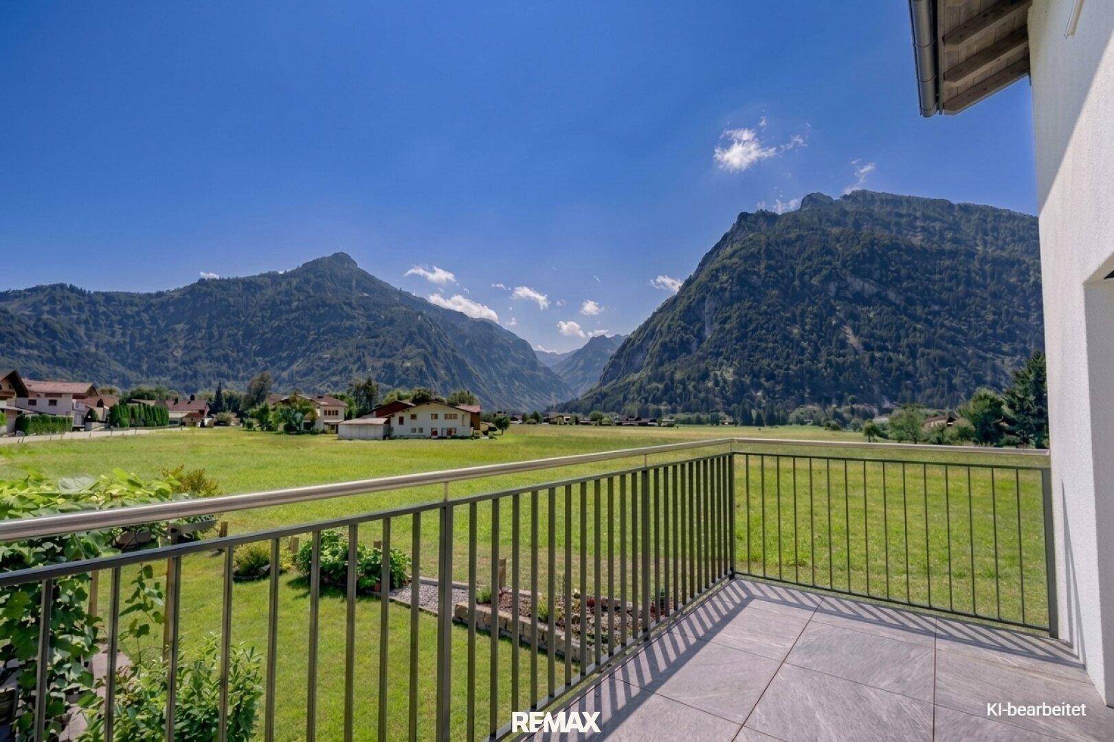 Geräumiger Balkon mit Fliesenboden und einem weiten Blick über grüne Felder und majestätische Berge.