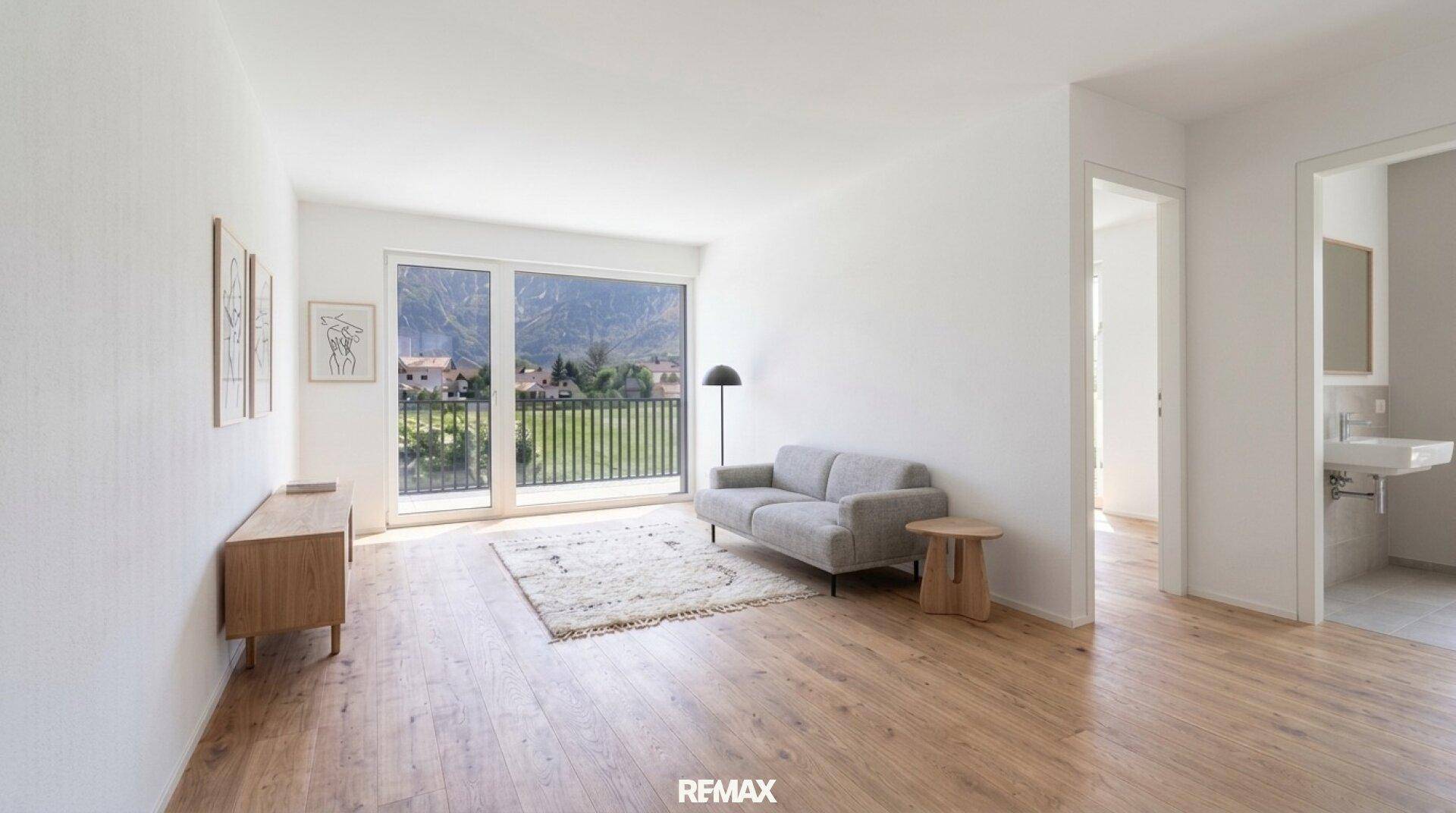 Helles Wohnzimmer mit Holzboden, modernem Sofa und Zugang zu einem Balkon mit Bergblick.