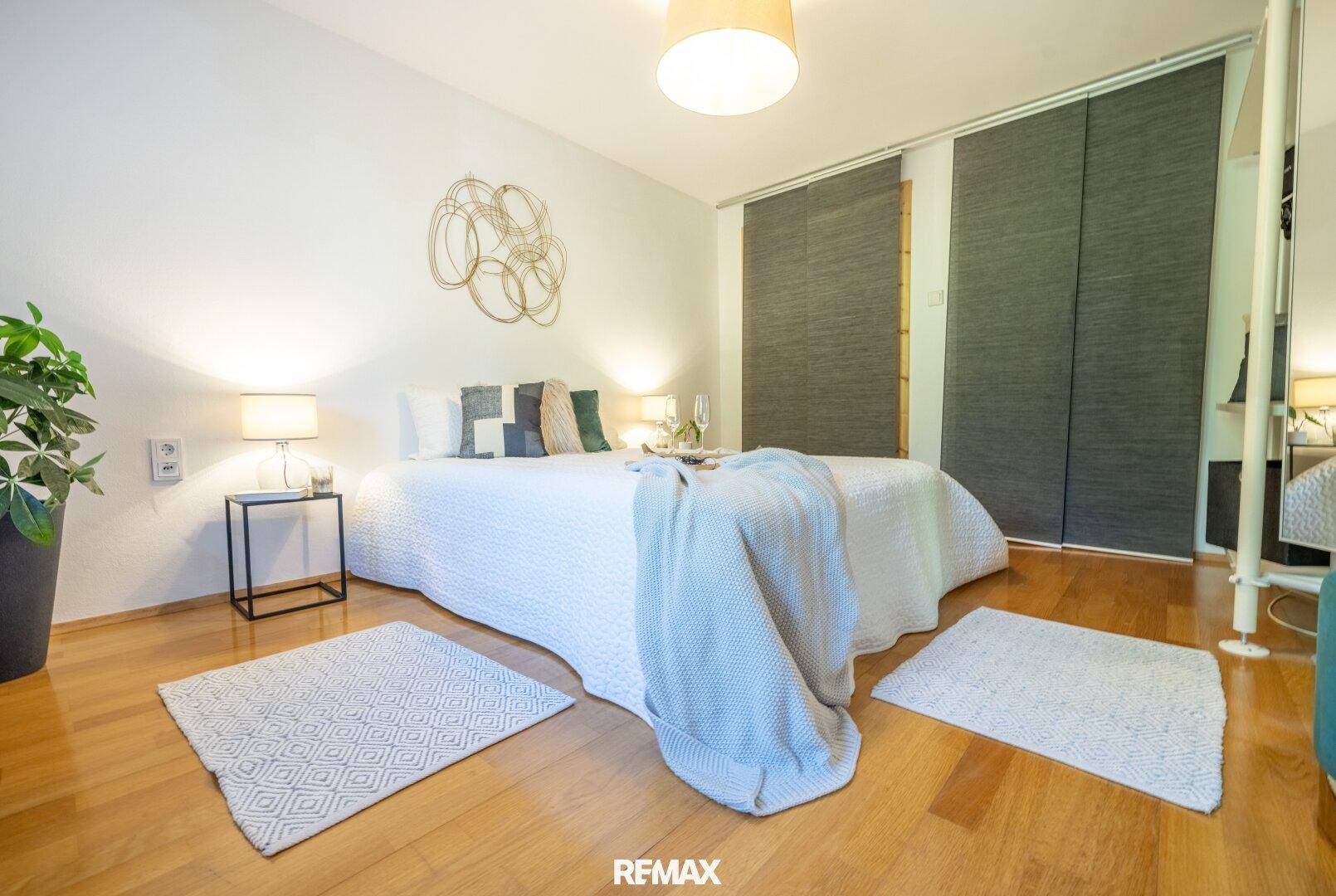 Helles Schlafzimmer mit Holzboden, großem Bett und modernen Nachttischen.