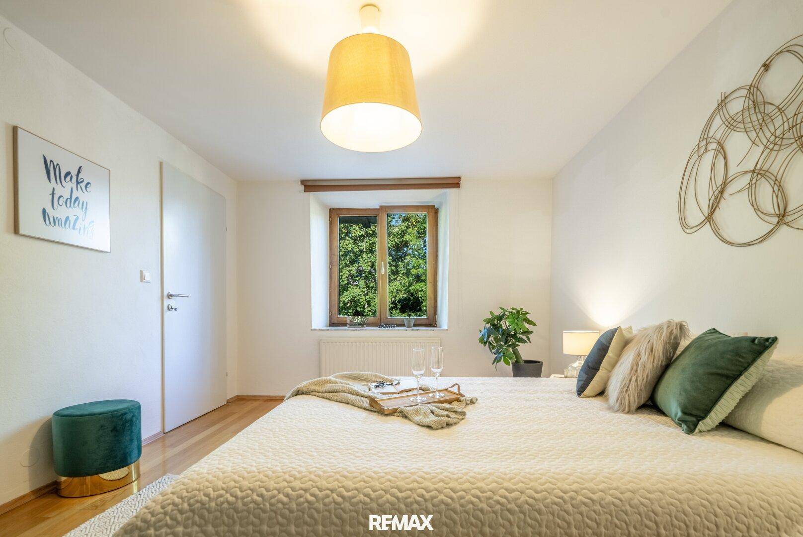 Ruhiges Schlafzimmer mit Holzboden, großem Bett und Blick ins Grüne.