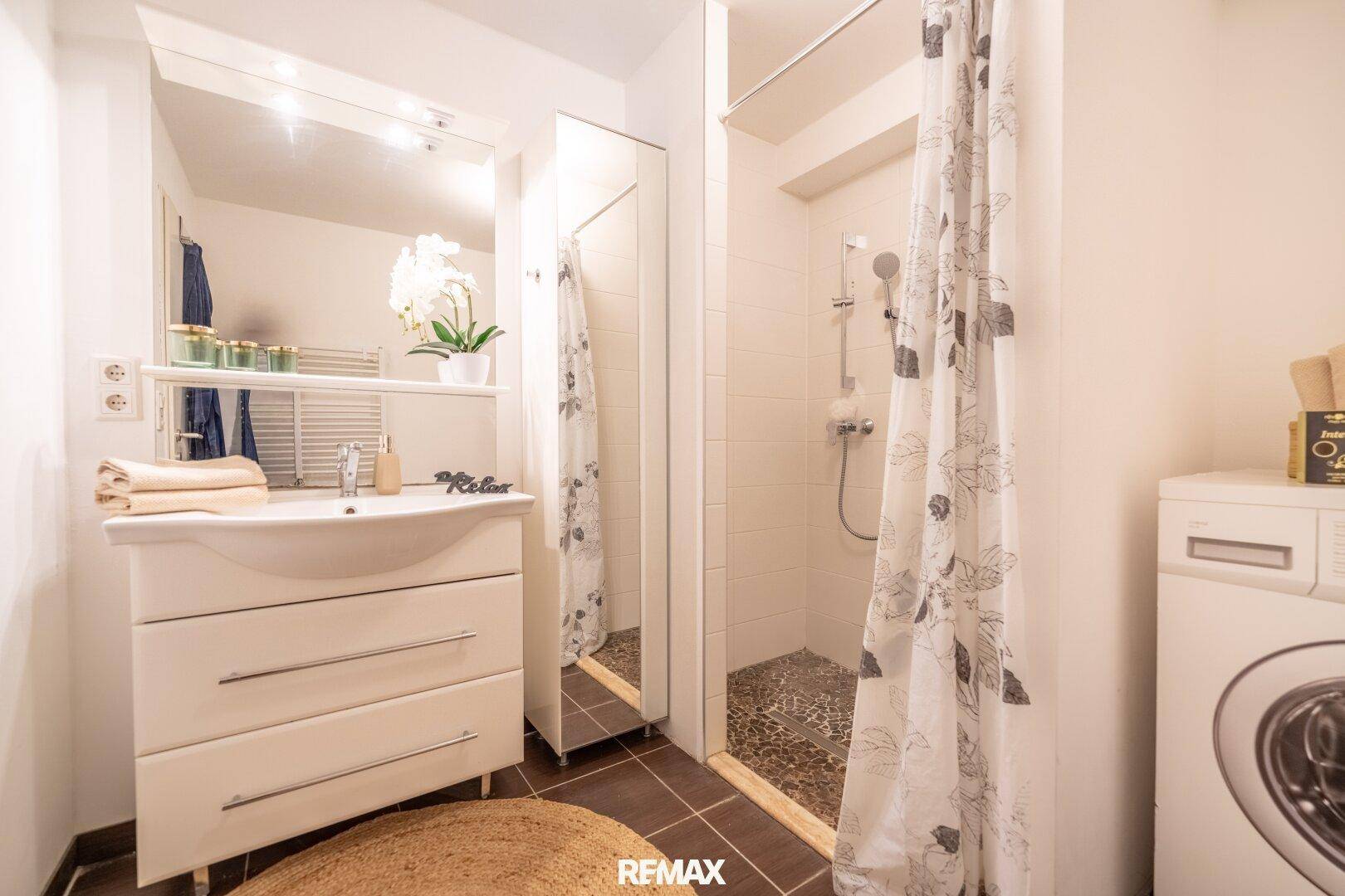 Modernes Badezimmer mit Dusche, Waschbecken und Waschmaschine.
