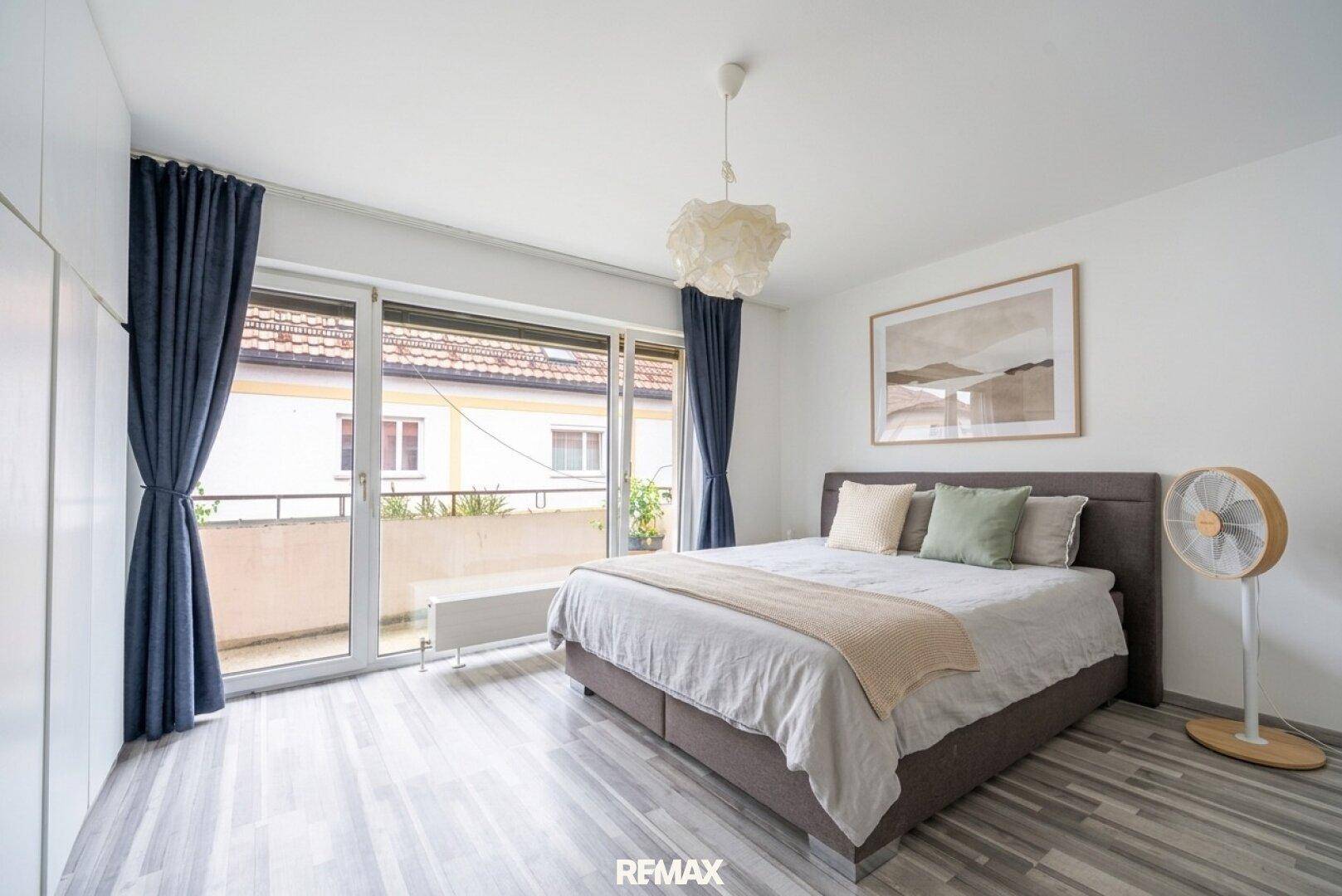Helles Schlafzimmer mit Doppelbett, modernem Boden und direktem Zugang zum Balkon.