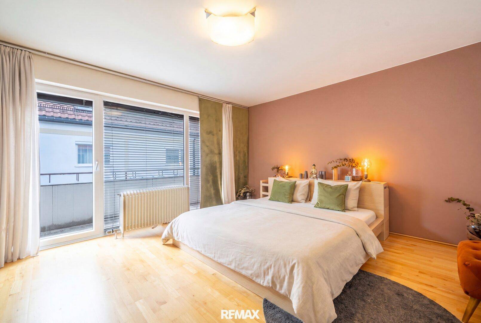 Helles Schlafzimmer mit Holzboden, großem Bett und direktem Zugang zum Balkon.
