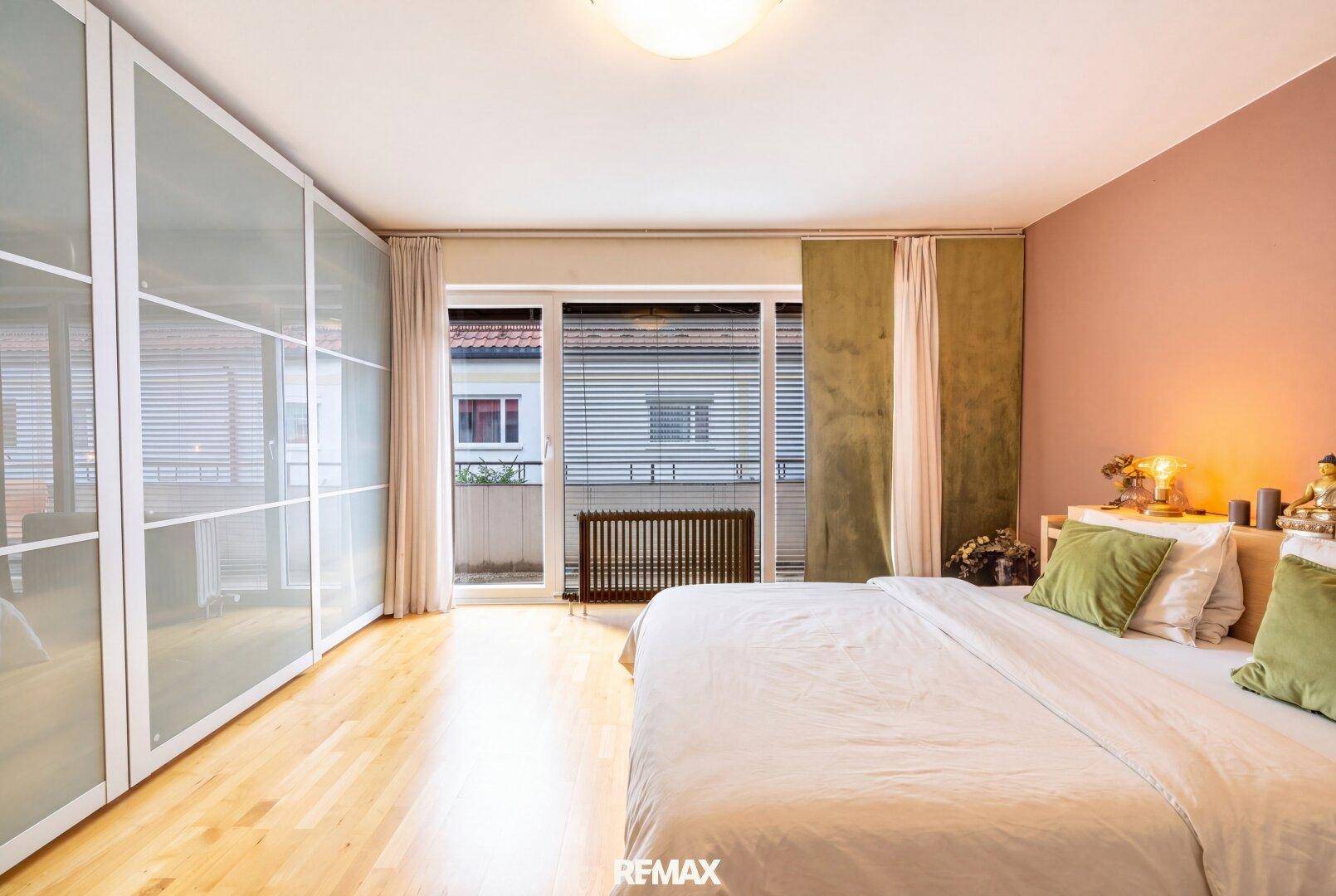 Geräumiges Schlafzimmer mit Einbauschränken, Holzboden und Balkonzugang.