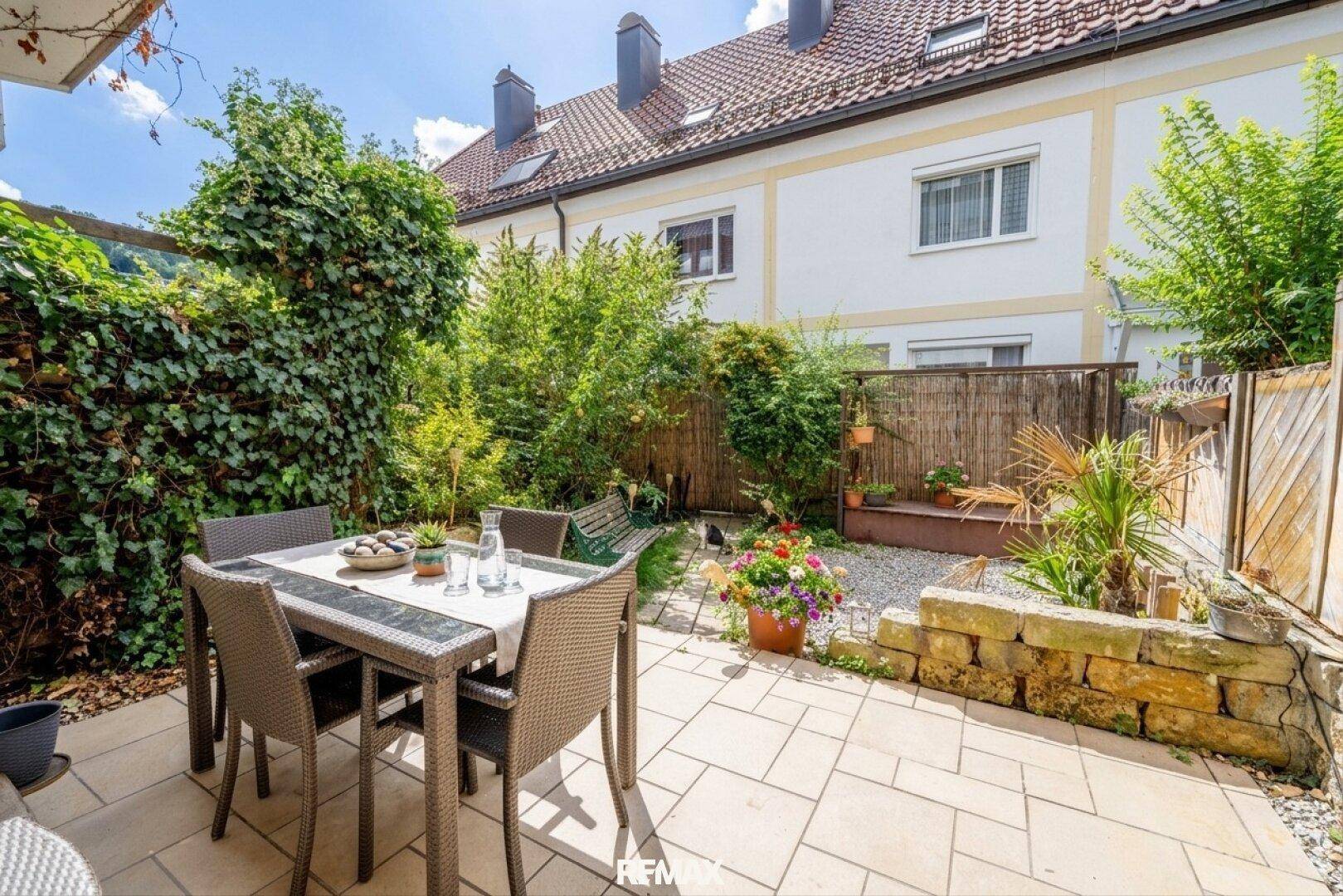 Gemütlicher Gartenbereich mit gepflasterter Terrasse, Sitzgelegenheiten und üppiger Bepflanzung.