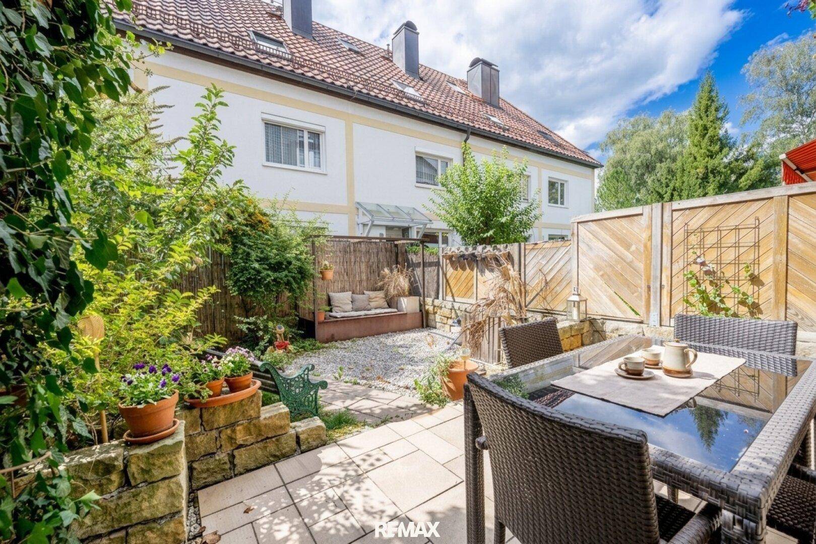 Gepflegter Gartenbereich mit Terrasse, Sitzgelegenheiten und üppiger grüner Bepflanzung.