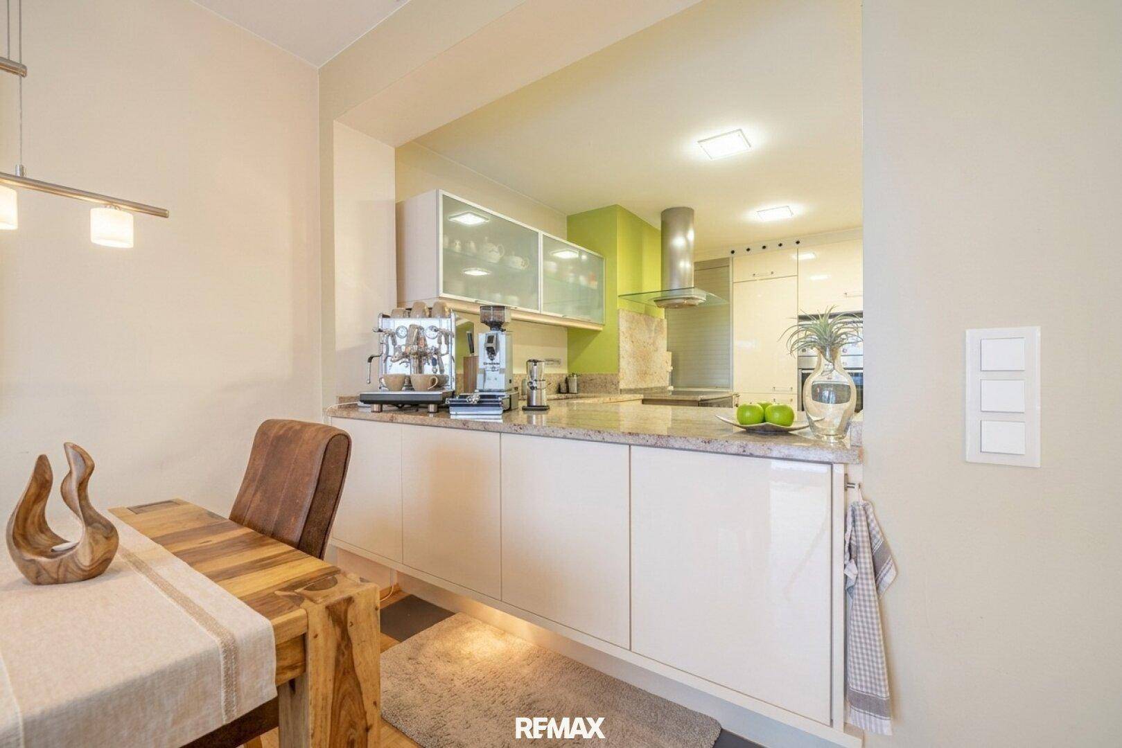 Moderne Küche mit hellen Schränken, Granitarbeitsplatte und integrierter Kaffeemaschine.