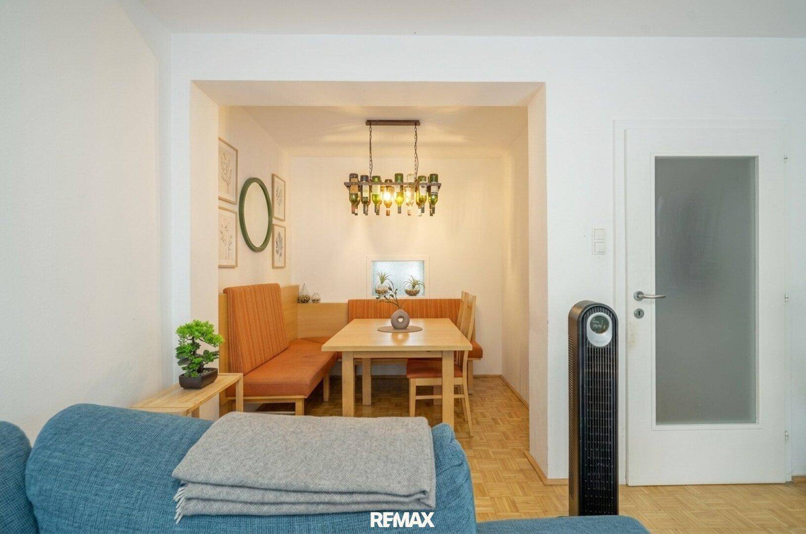 Gemütlicher Essbereich mit Holztisch und Sitzbank, kreativ beleuchtet durch eine Flaschenlampe.