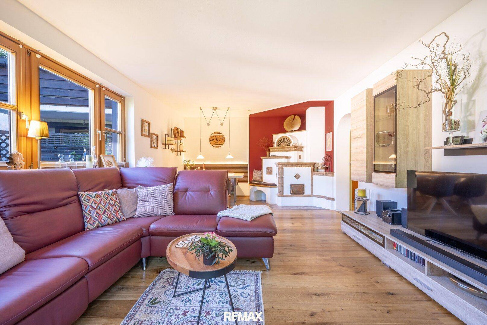 Geräumiges Wohnzimmer mit rotem Ledersofa, Holzboden und Blick auf den Essbereich.