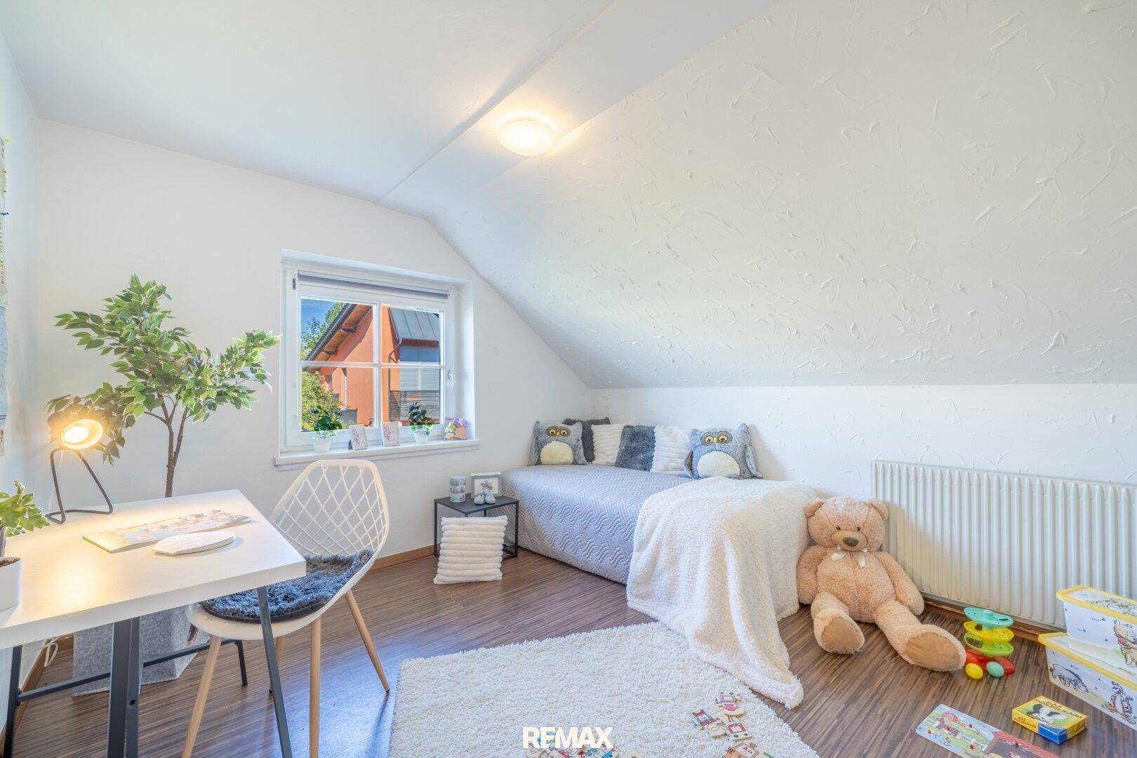 Kinderzimmer im Dachgeschoss mit schräger Decke, Einzelbett und Schreibtisch, hell und freundlich.