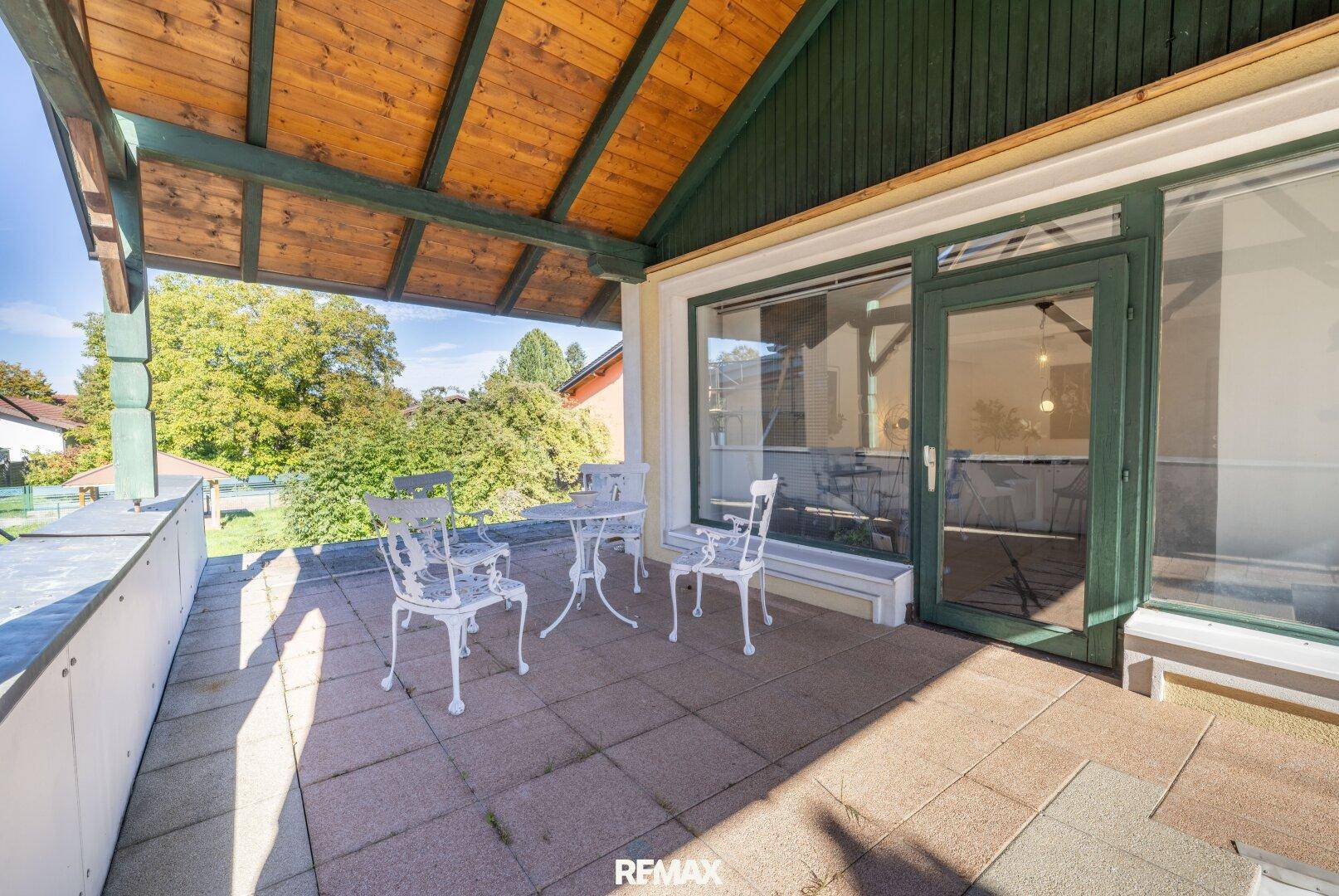 Überdachte Loggia mit Gartenmöbeln und Blick ins Grüne, ideal für entspannte Stunden im Freien.