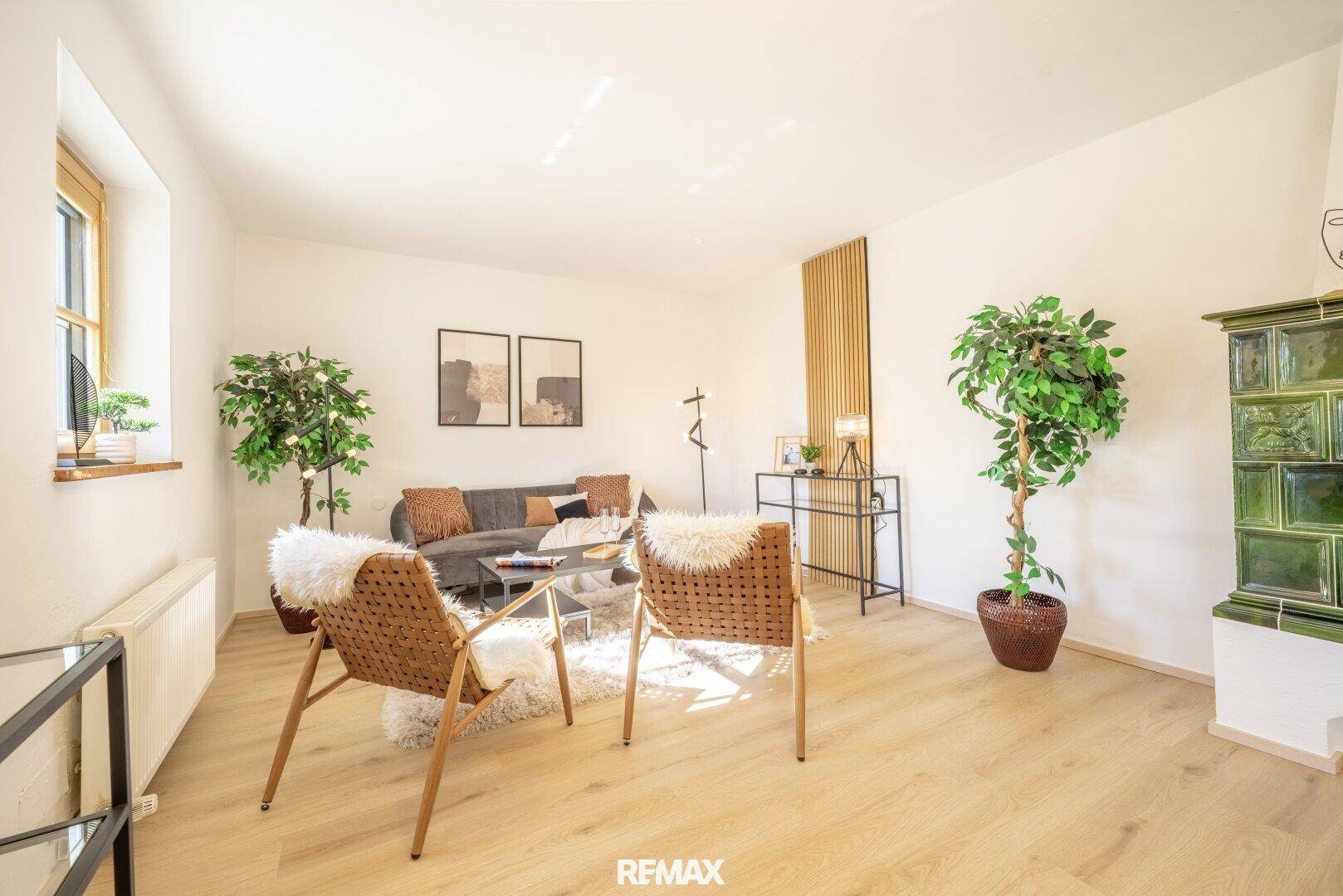 Helles Wohnzimmer mit bequemen Sitzgelegenheiten, Kachelofen und Blick ins Grüne.