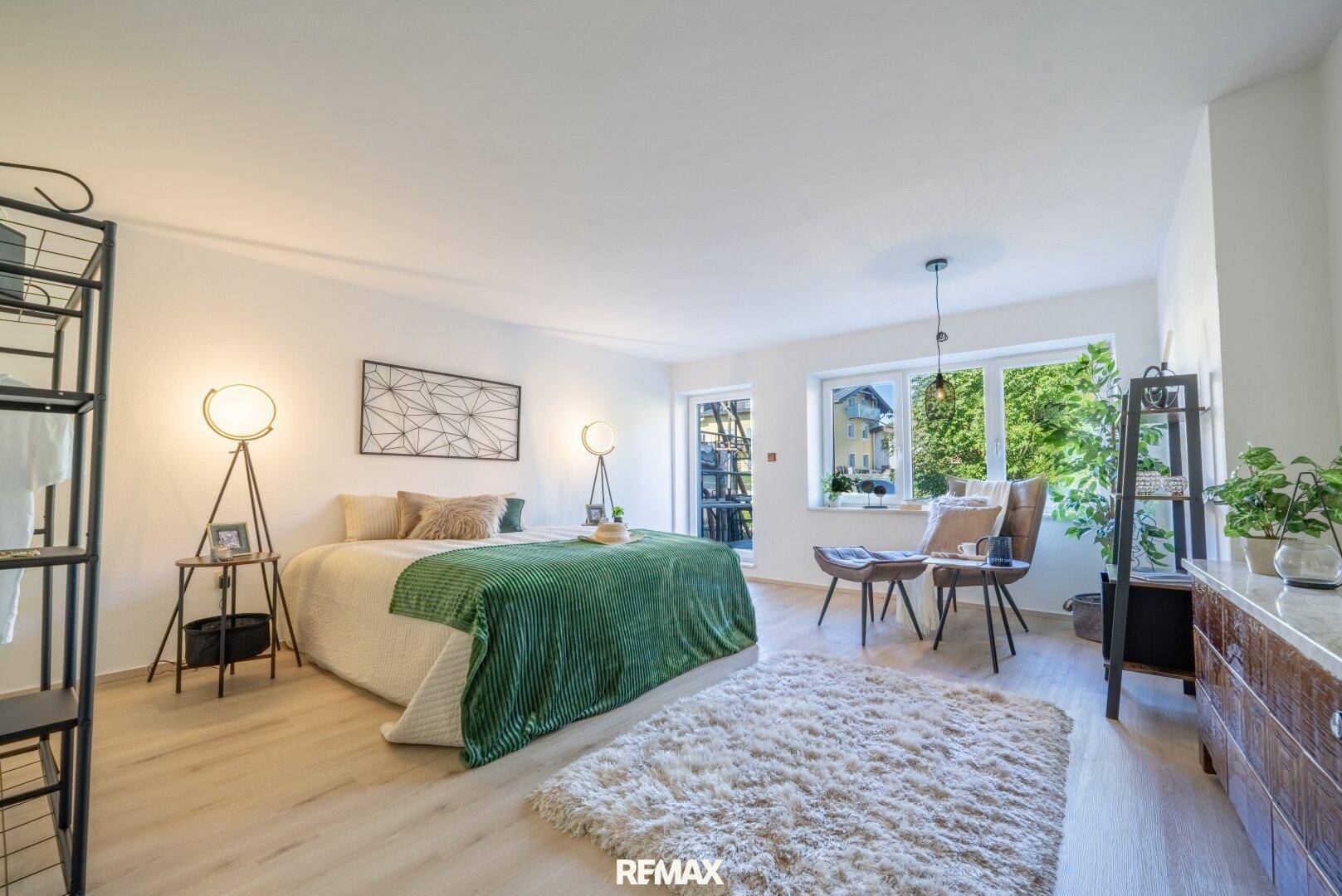 Helles Schlafzimmer mit großem Bett, modernen Stehlampen und hellem Laminatboden.