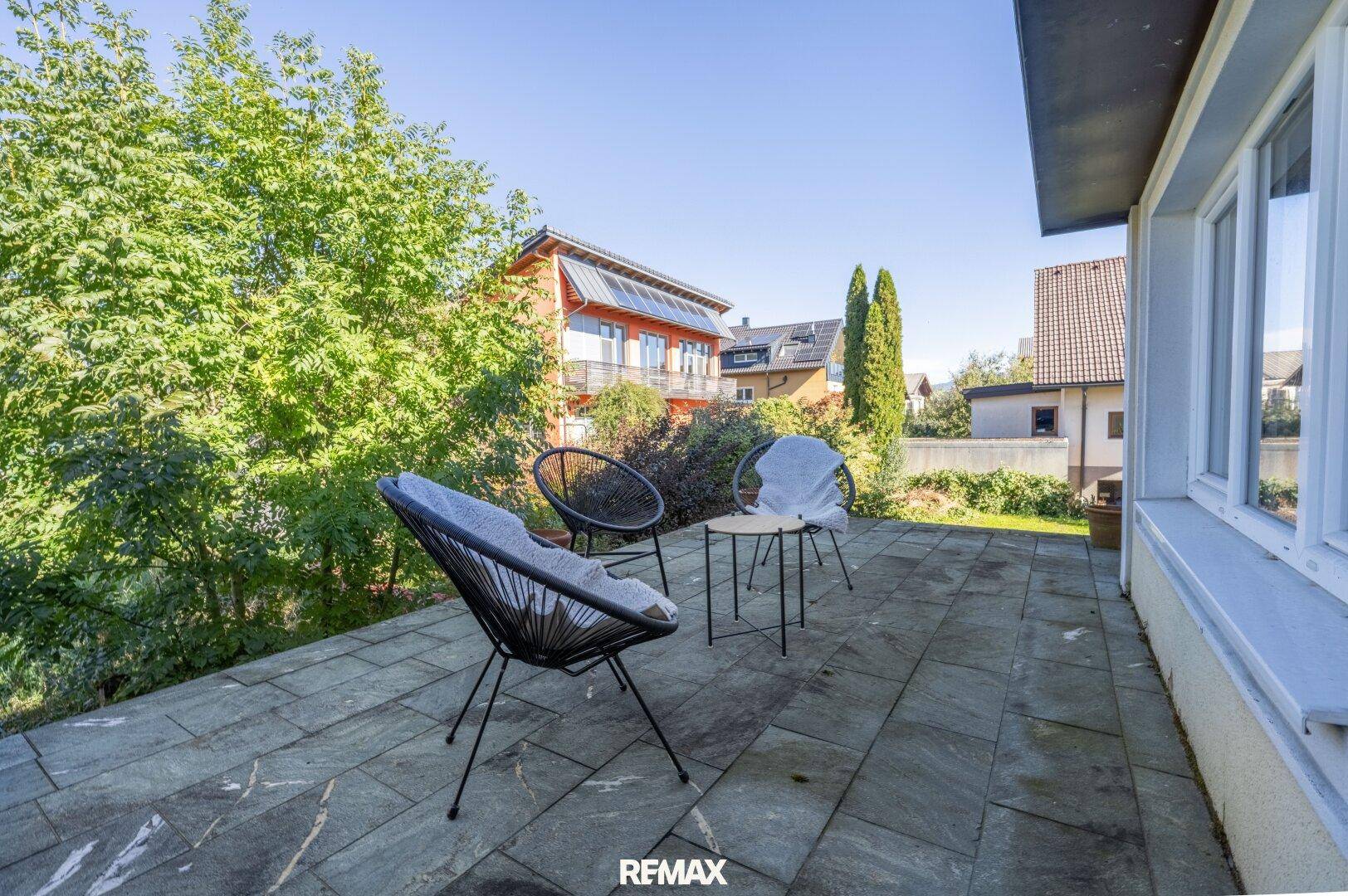 Gepflasterte Terrasse mit modernen Gartenmöbeln und umgebender Bepflanzung.
