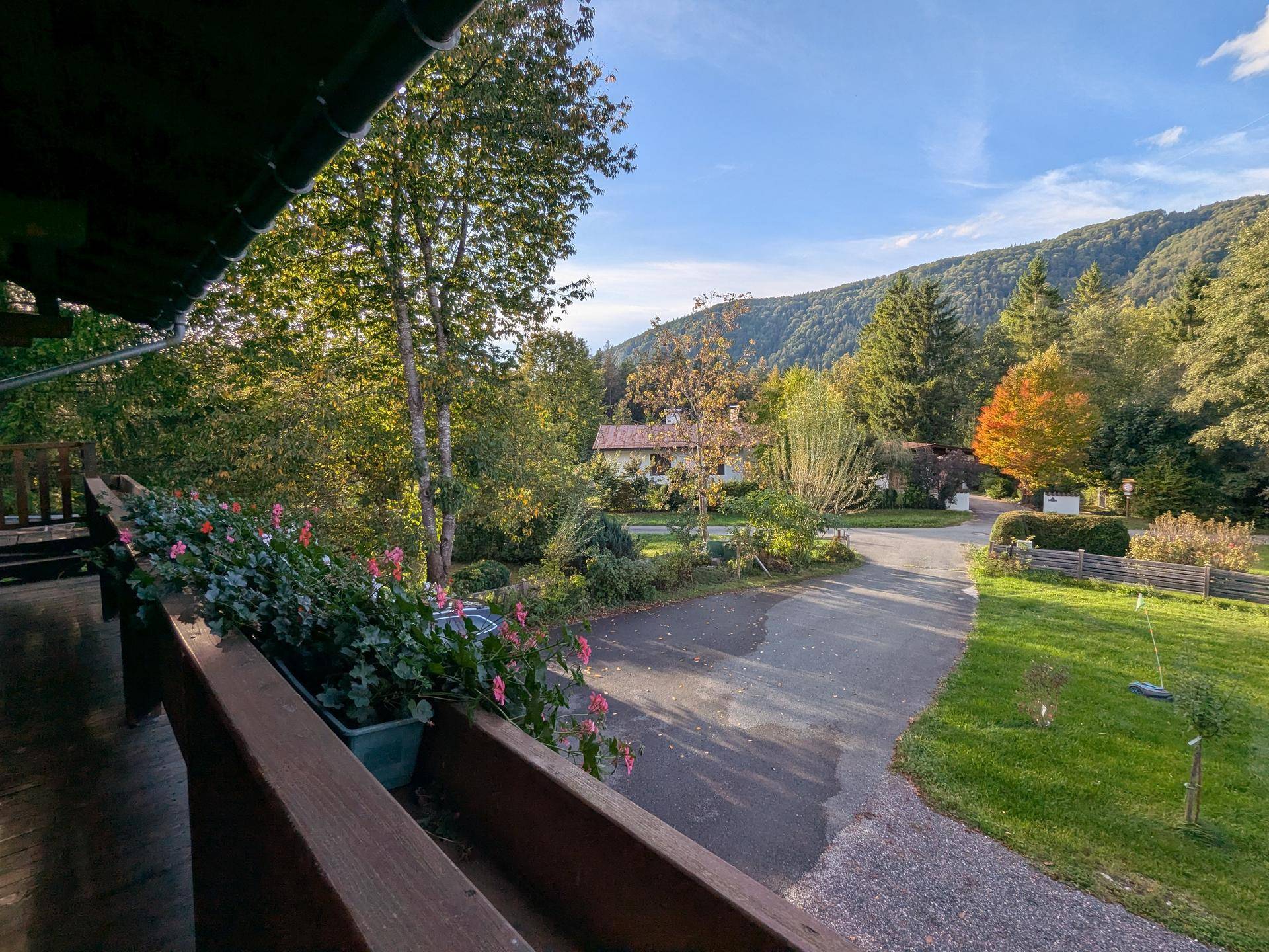 Balkon mit Blumenkästen und Blick auf den Garten, die Zufahrt und die umliegende Natur.